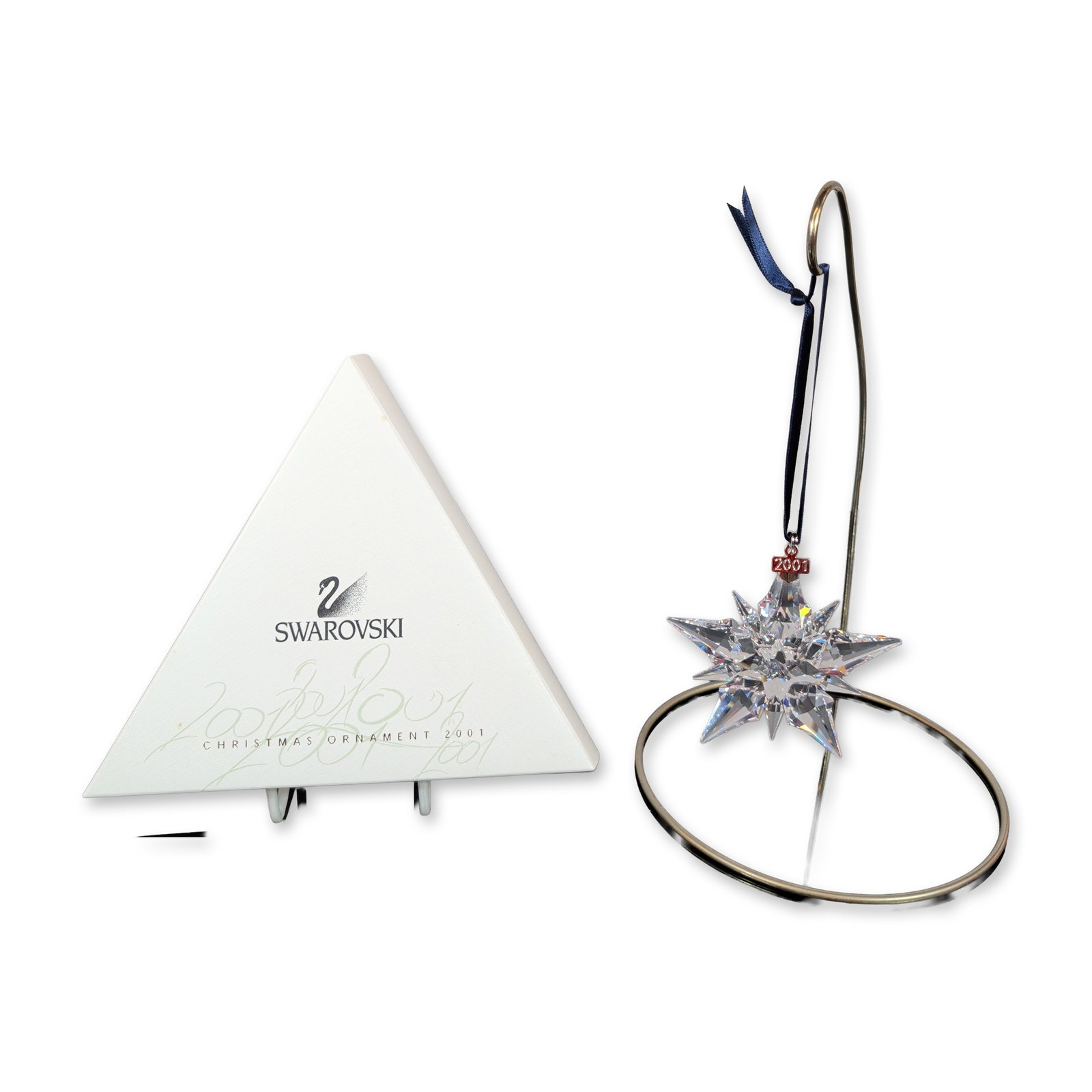 Swarovski 2001 Crystal Christmas Star Ornament: Swarovski. Annual Edition Christmas star ornament, 2001. Faceted lead crystal ornament featuring multiple radiating points in a tiered configuration. Includes a silver-toned metal hang tag incised wit