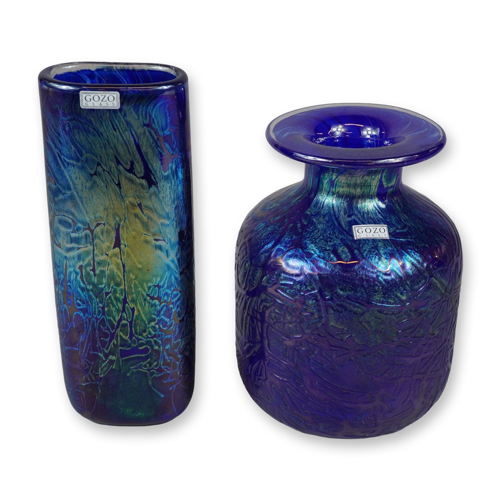 2pc Gozo Glass Iridescent Studio Glass Vases: Two pieces of hand-blown iridescent studio glass produced by Gozo Glass in Malta. The first piece is a tall vase with a flattened rectangular profile, decorated with a marbled pattern of cobalt blue a