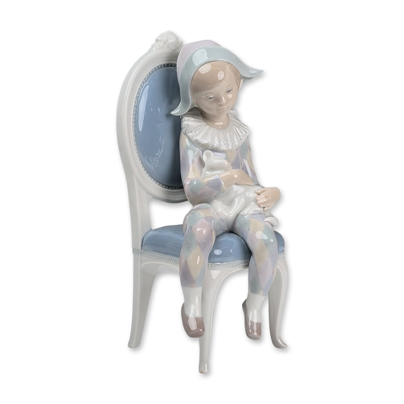 Lladro Glazed Porcelain Figurine, Young Harlequin 01001229: Lladro (Spain). Figurine in glazed porcelain designed by Fulgencio Garcia. The piece depicts a young boy in a pastel-colored harlequin suit with a white ruff collar and pointed cap, seated in a Louis 