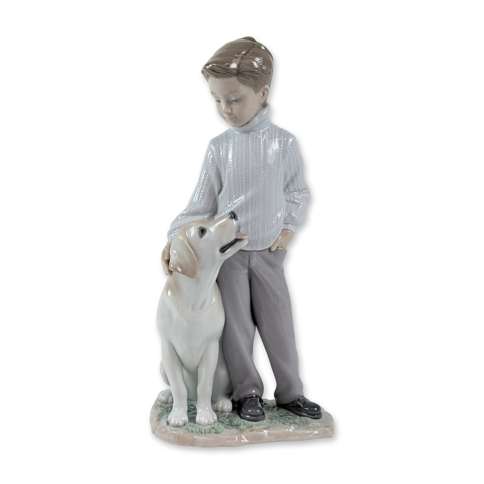 Lladro My Loyal Friend Porcelain Figurine: Lladro (Spain). Glazed porcelain figurine titled My Loyal Friend, model number 6902, sculpted by Ernest Massuet. The piece depicts a young boy in a textured cable-knit sweater and gray trousers standi