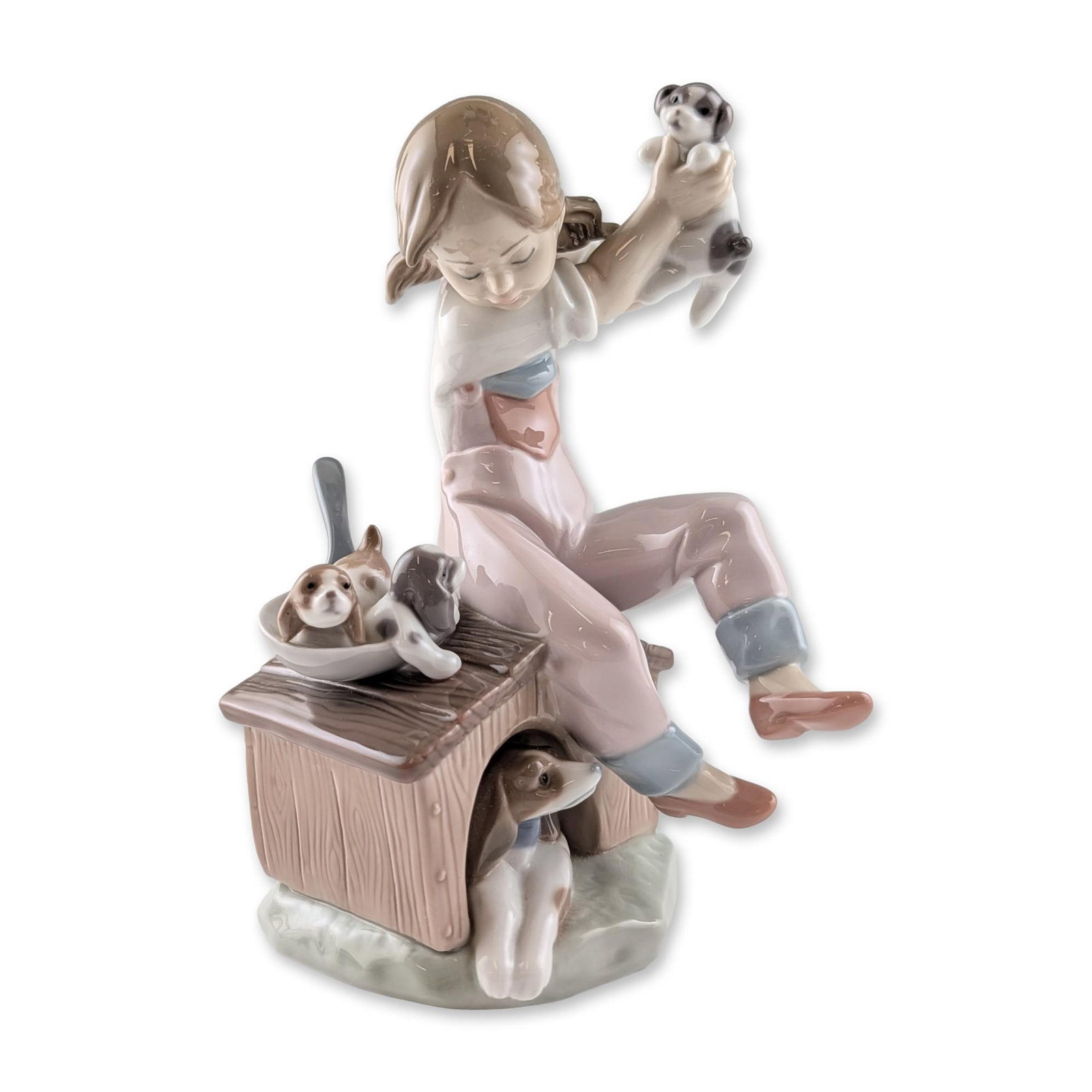Lladro Pick of Litter Porcelain Figurine: Lladro glazed porcelain figurine, model number 7621, titled Pick of Litter. The piece depicts a young girl in pink overalls and a white shirt seated on the roof of a wooden-textured doghouse. The girl
