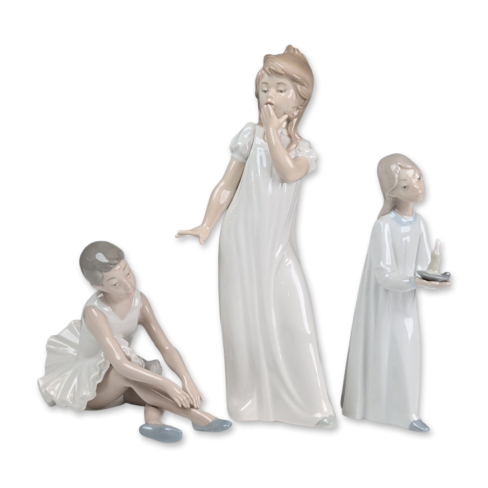 3pc Nao by Lladro Porcelain Figurines, Ballerina, Yawning & Girl with Candlestick: Group of three Nao by Lladro glazed porcelain figurines produced in Spain. The collection features youthful subjects in white attire: a standing girl in a puffed-sleeve nightgown yawning, a standing g