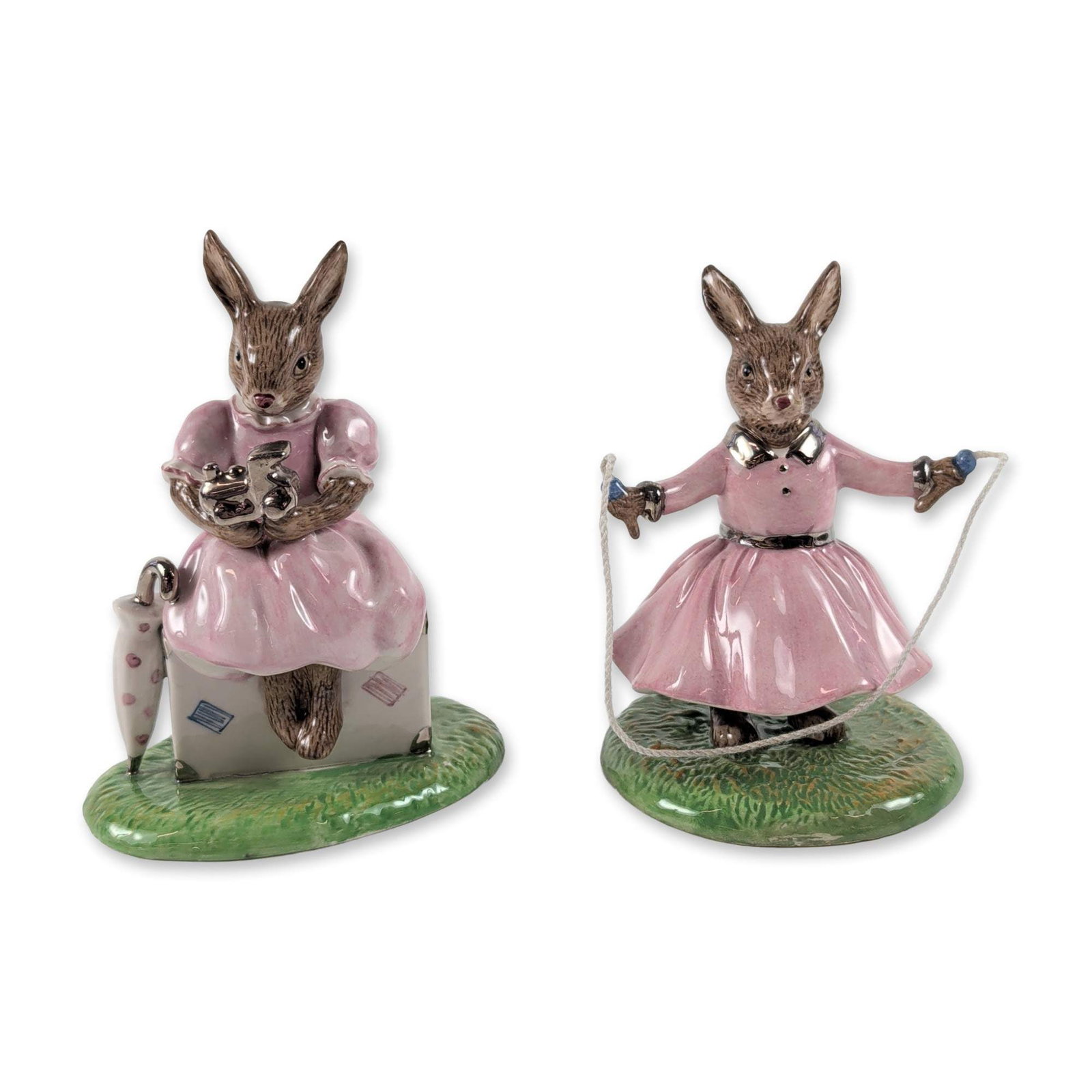 2pc Rare Royal Doulton Bunnykins Silver Limited Edition Figurines: Royal Doulton, England. Two hand-decorated glazed ceramic figurines from the Bunnykins series, Sitting On A Suitcase (DB 482) and Polly (DB 484). Sitting On A Suitcase shows a rabbit in a pink dress p
