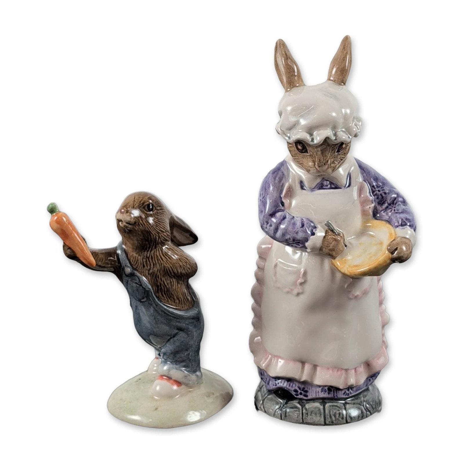 2pc Beswick and Royal Doulton Figurines: English glazed ceramic rabbit figurines from Beswick and Royal Doulton. Includes Mrs. Rabbit Baking (ECF7) depicted in a purple dress and white apron, and Bunnykins Mother's Day (DB 155) depicted in b