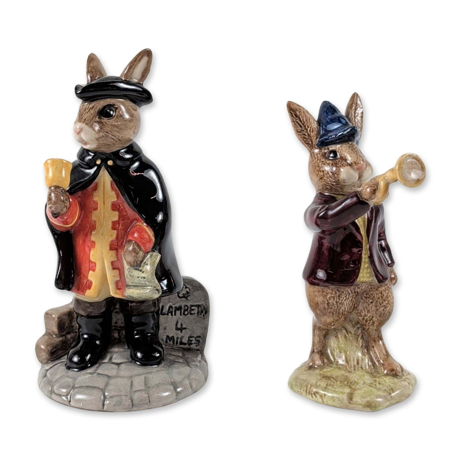 2pc Royal Doulton Bunnykins Ceramic Figurines: Royal Doulton. Pair of Bunnykins figurines in glazed ceramic, featuring anthropomorphic rabbits. Includes Rise and Shine (DB 11), depicting a rabbit in a maroon coat and blue cap blowing a horn on a g