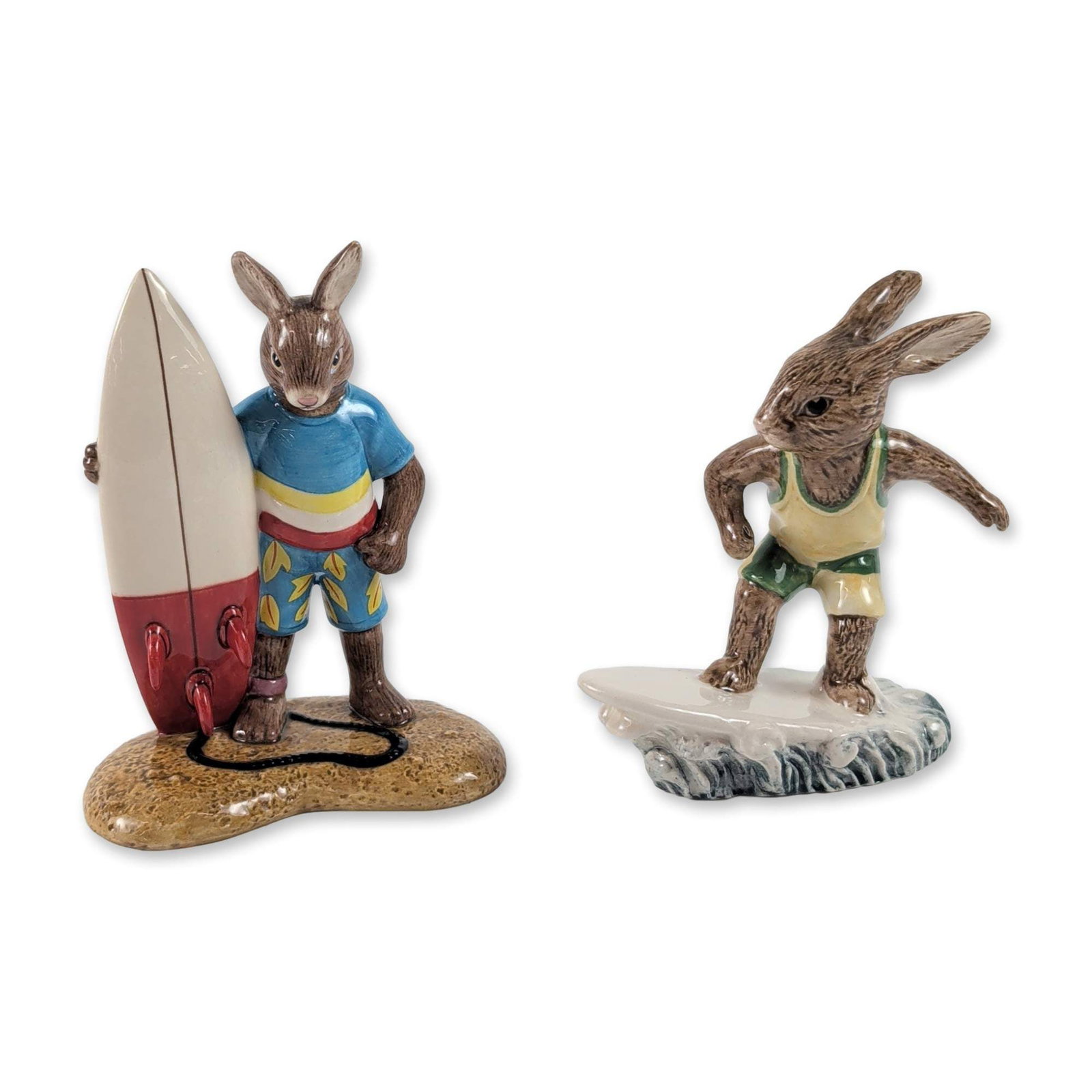 2pc Royal Doulton Bunnykins Surfing Figurines: Two Royal Doulton Bunnykins hand-decorated earthenware figurines with a surfing theme, produced for the Australian market. The first figurine, titled Aussie Surfer (DB 133), depicts a rabbit riding a 