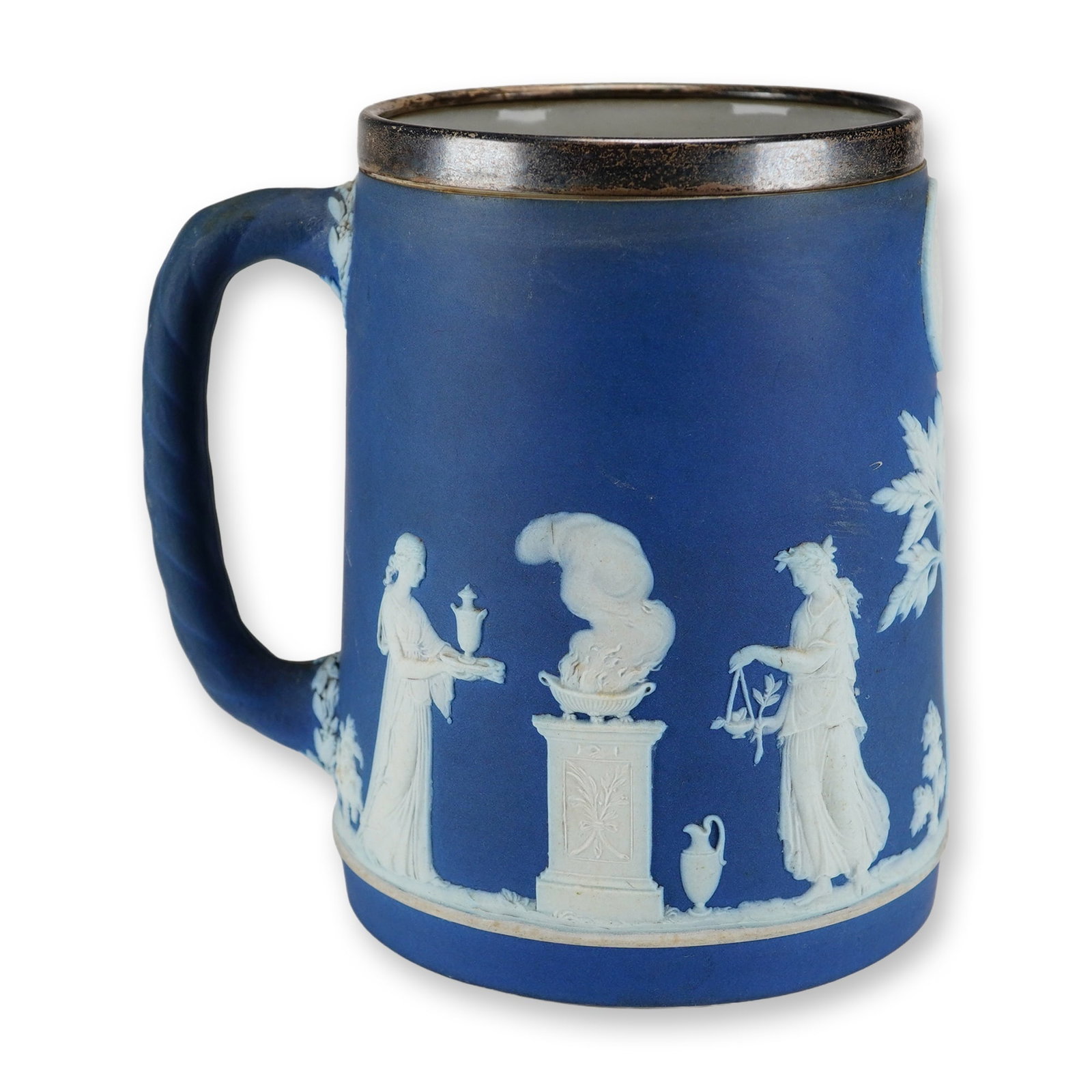 Wedgwood Cobalt Blue Jasperware Mug with Elkington and Co Sterling Silver Rim: This cylindrical mug is manufactured from cobalt blue jasperware by Wedgwood and features a sterling silver rim mount applied by Elkington and Co. Ltd. of Birmingham, England. The exterior is decorate