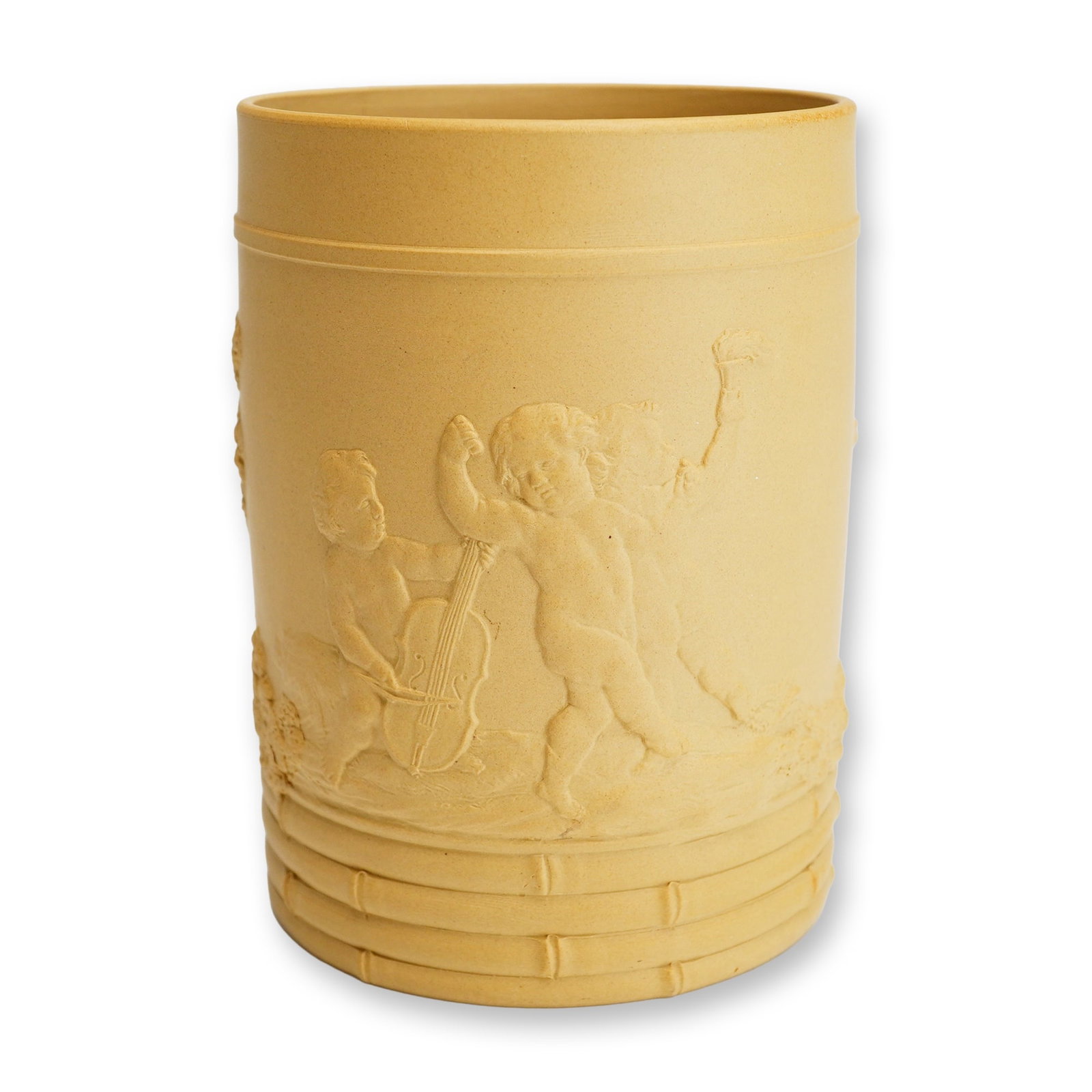 Wedgwood Caneware Mug Depicting Cupids Playing Music and Dancing: A Wedgwood caneware mug crafted from buff-colored, unglazed stoneware with sprigged relief ornamentation. The central decorative scene depicts three putti within a landscape; one figure is seated play