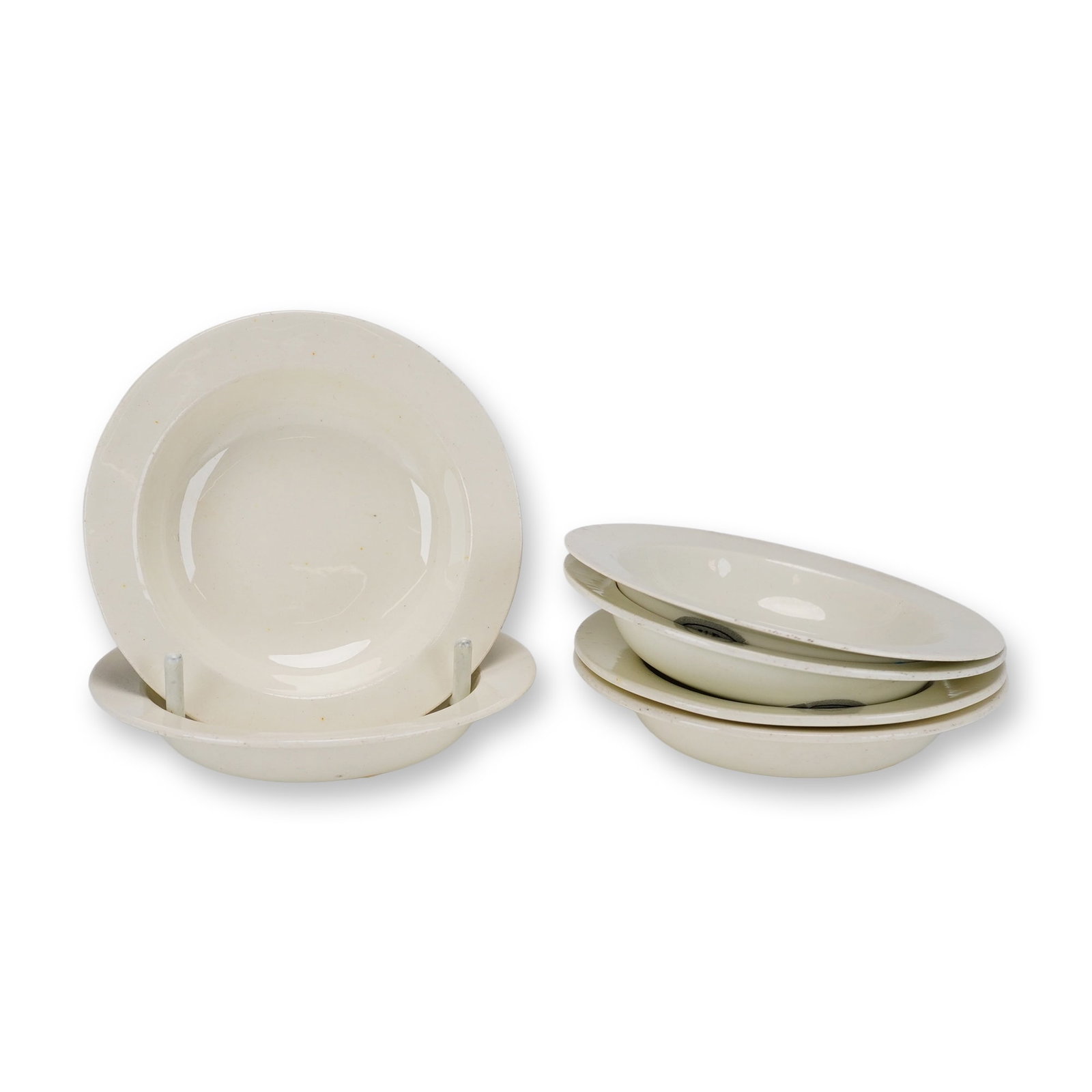 6pc Wedgwood Creamware Rimmed Bowls: A set of six shallow rimmed bowls crafted in cream-colored earthenware by Wedgwood. Each bowl features a minimalist design with a wide, flat rim surrounding a shallow central well, characteristic of c