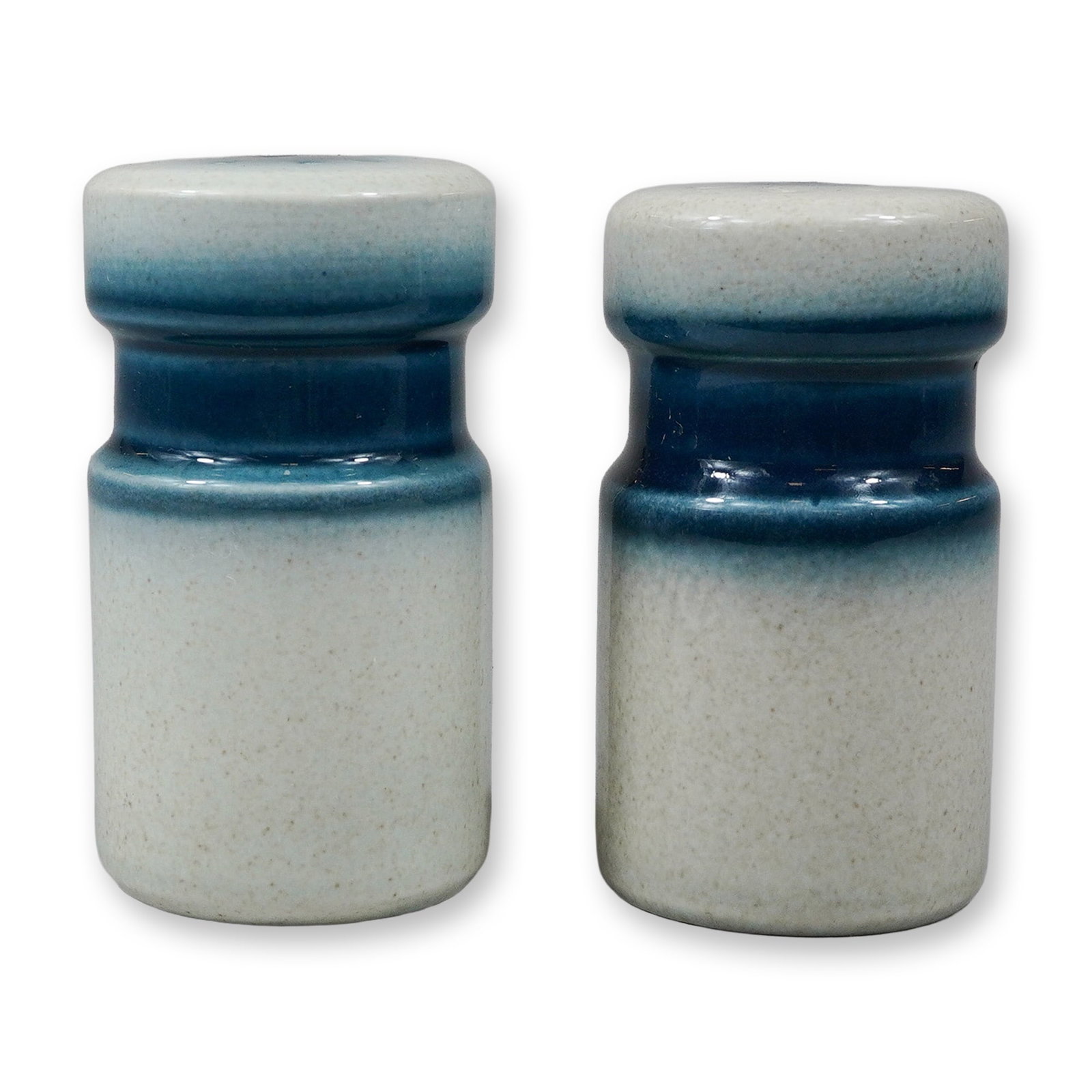 A Pair of Wedgwood Blue Pacific Stoneware Salt and Pepper Shakers: This pair of stoneware salt and pepper shakers is produced in the Blue Pacific pattern by Wedgwood. The shakers feature a cylindrical form with a waisted neck and a shallow-domed top. They are finishe