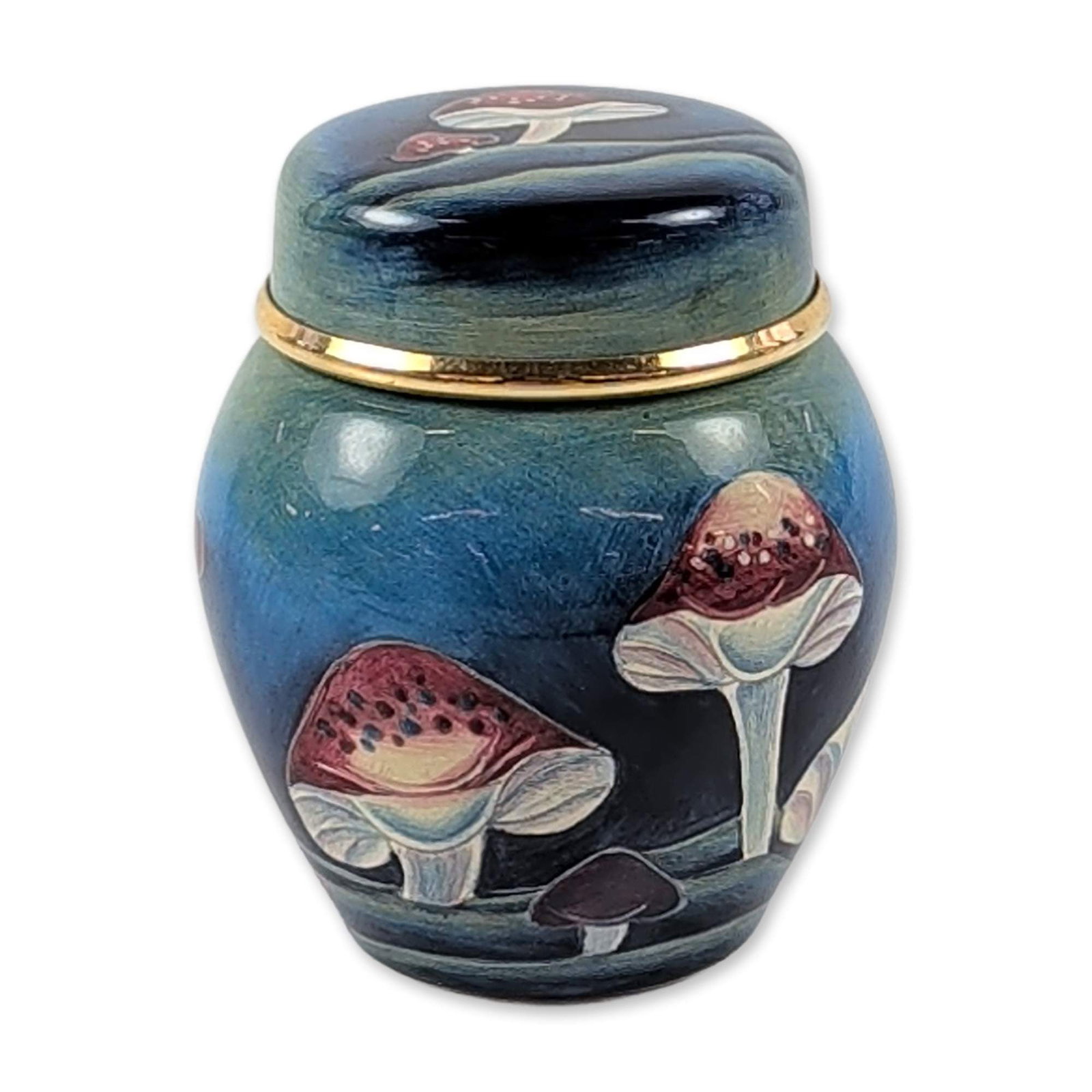 Moorcroft Miniature Claremont Mushroom Ginger Jar: Moorcroft, England, 1999. Miniature lidded ginger jar in glazed earthenware, featuring a tube-lined mushroom pattern in red, cream, and purple over a graduated teal and black ground. The piece is