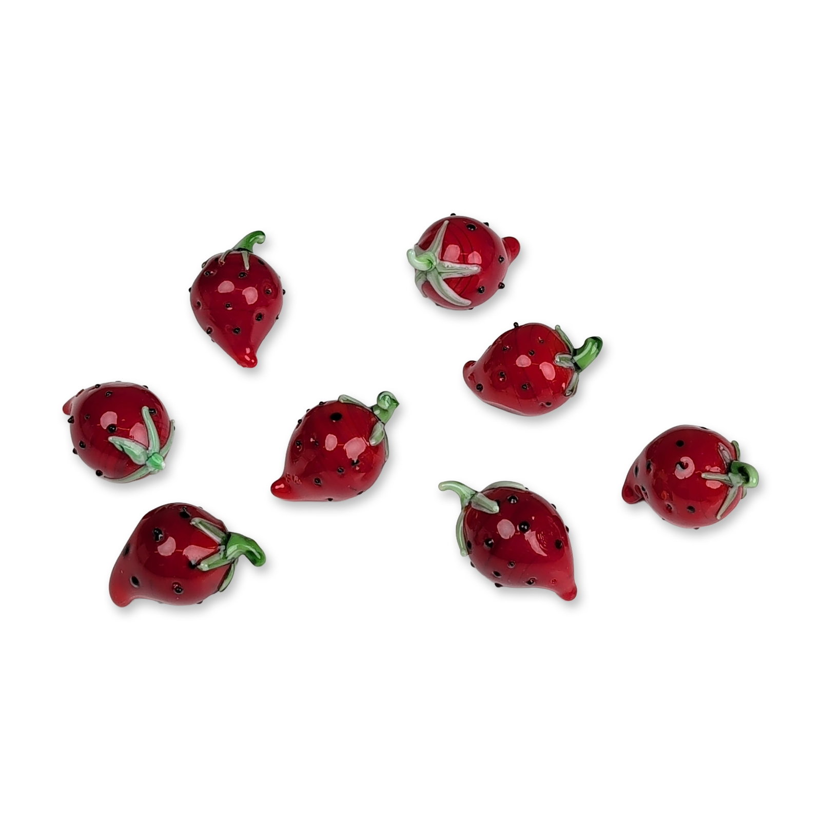 Group of Eight Lampworked Art Glass Strawberries: Contemporary decorative art glass. Group of eight strawberries in lampworked glass, featuring red bodies with applied black seeds and light green stems and sepals. The green glass elements display int