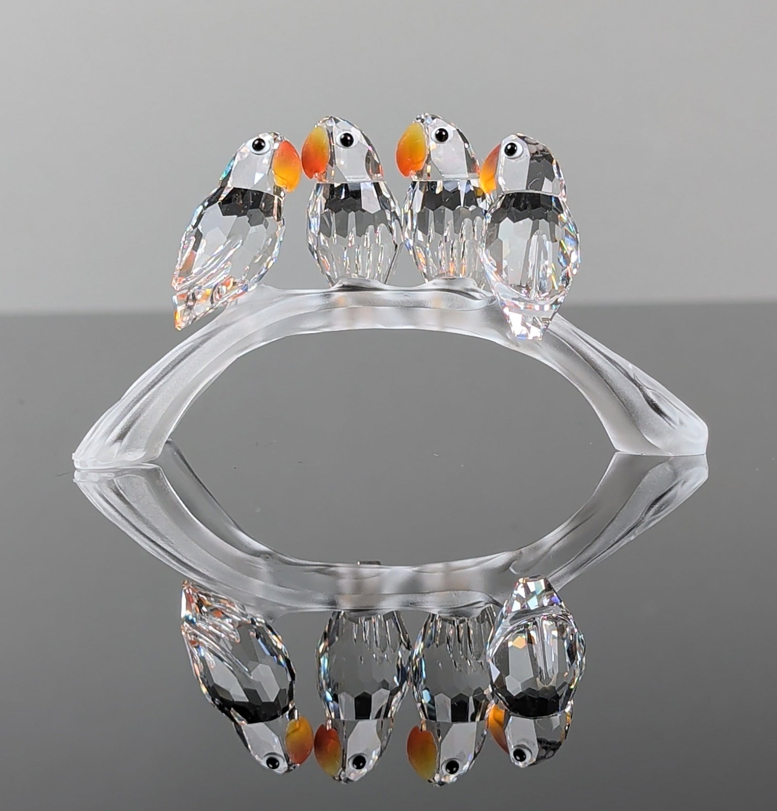 Swarovski Crystal Figurine, Baby Lovebirds: Crystal figurine in clear faceted crystal and frosted glass, depicting a group of baby lovebirds on a frosted glass branch. The birds feature faceted bodies, smooth heads, black inset eyes, and orange