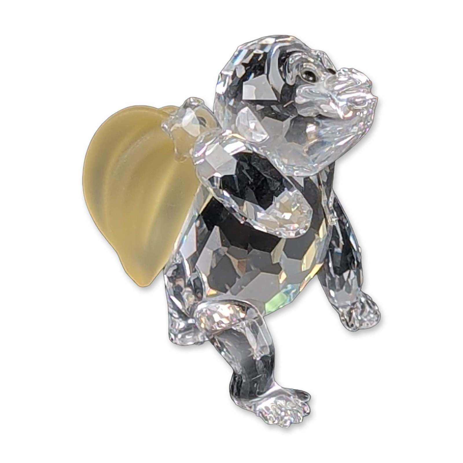 Swarovski Crystal Figurine, Young Gorilla: Young gorilla figurine in faceted clear lead crystal from the African Wildlife series. The piece is modeled in a quadrupedal stance and features a frosted yellow crystal bunch of bananas on its back. 