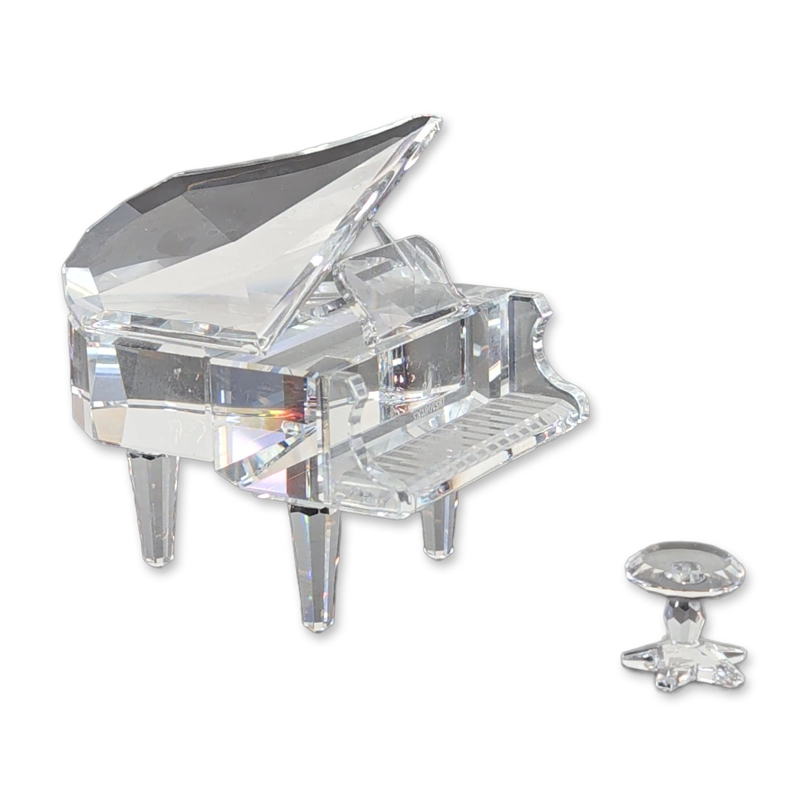 Swarovski Crystal Grand Piano and Stool: Swarovski. A grand piano and stool set in faceted clear crystal, featuring a propped lid design supported by a thin rod, three tapered legs, and a separate round piano stool on a pedestal base. The un