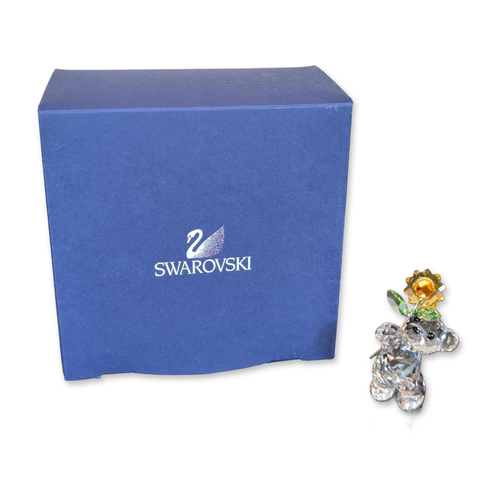 Swarovski Crystal Kris Bear Especially For You Figurine: Swarovski faceted crystal figurine from the Kris Bear collection. The clear crystal bear is depicted holding a sunflower featuring a yellow and amber faceted crystal head and two green crystal leaves 