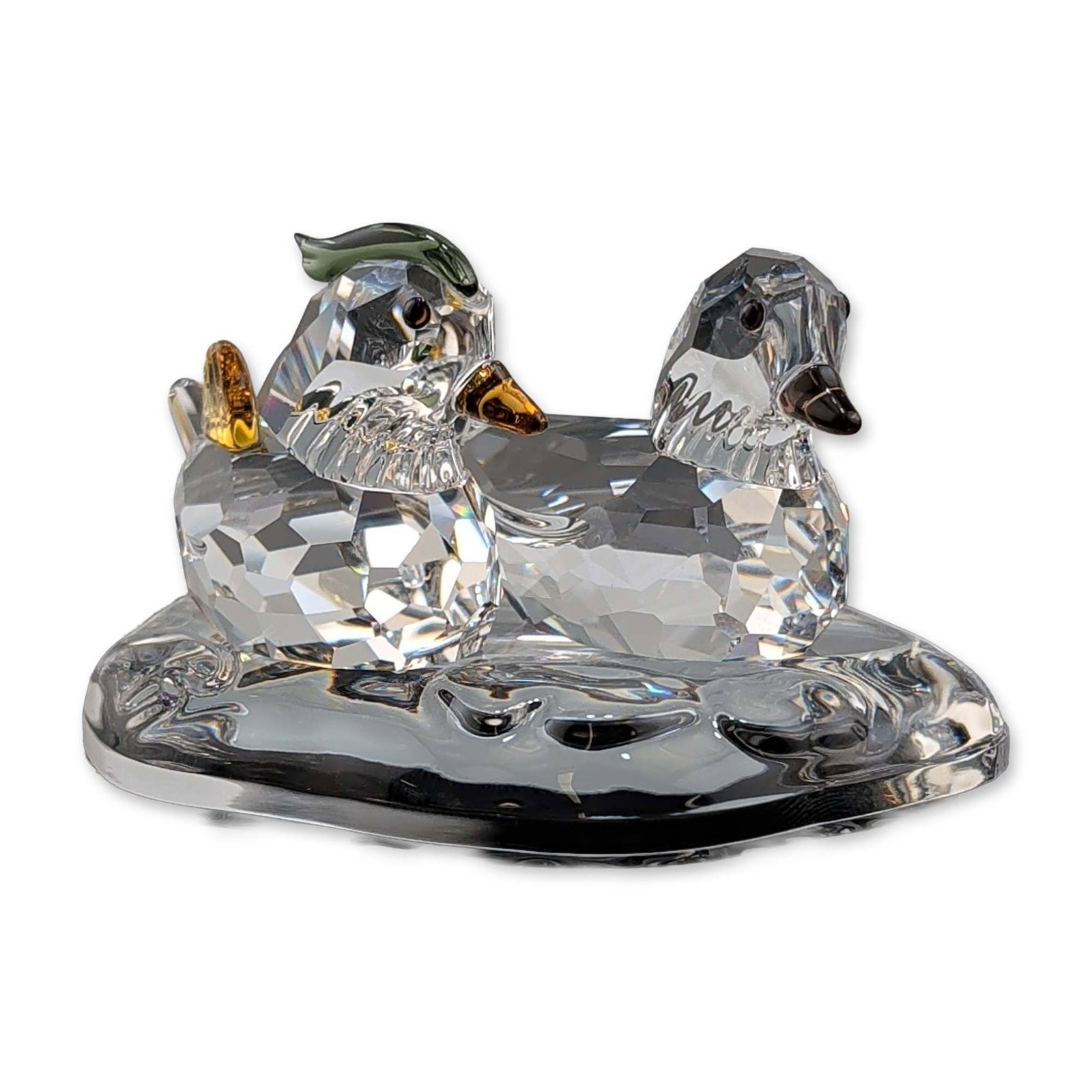 Swarovski Crystal Mandarin Ducks on Pond Figurines: Swarovski faceted lead crystal figurines, Mandarin Ducks on Pond, featuring a pair of ducks positioned on a textured clear crystal base. The male duck is detailed with a green-tinted crest, and yellow