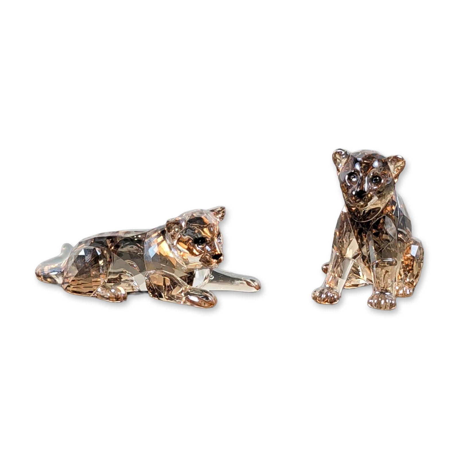 2pc Swarovski SCS 2010 Amur Leopard Cubs: Swarovski tiger cub figurines in Golden Shadow faceted lead crystal, modeled in various poses. Both examples bear the laser-etched Swarovski swan logo. Accompanied by original brand-marked blue box.Tw