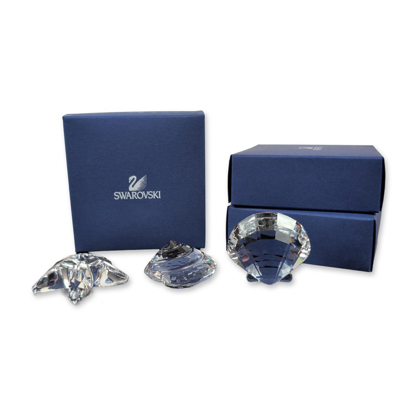 Three Swarovski Crystal Sea Life Figurines: This beautiful set of three Swarovski faceted clear lead crystal figurines captures the elegance of marine life, featuring a starfish, a scallop shell, and a spiral conch shell, each with the iconic e