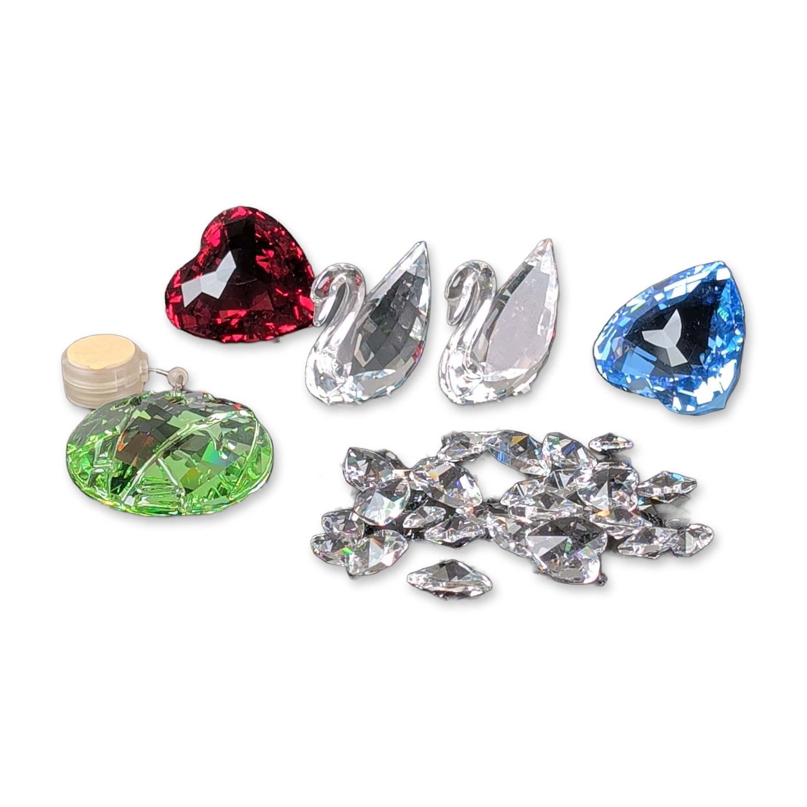 Six Piece Collection of Swarovski Crystal Figurines and Decorative Items: Swarovski. Collection of faceted crystal figurines and objects. The group includes faceted heart-shaped crystals in ruby red and light blue, clear crystal swan figurines with arched necks, and a facet