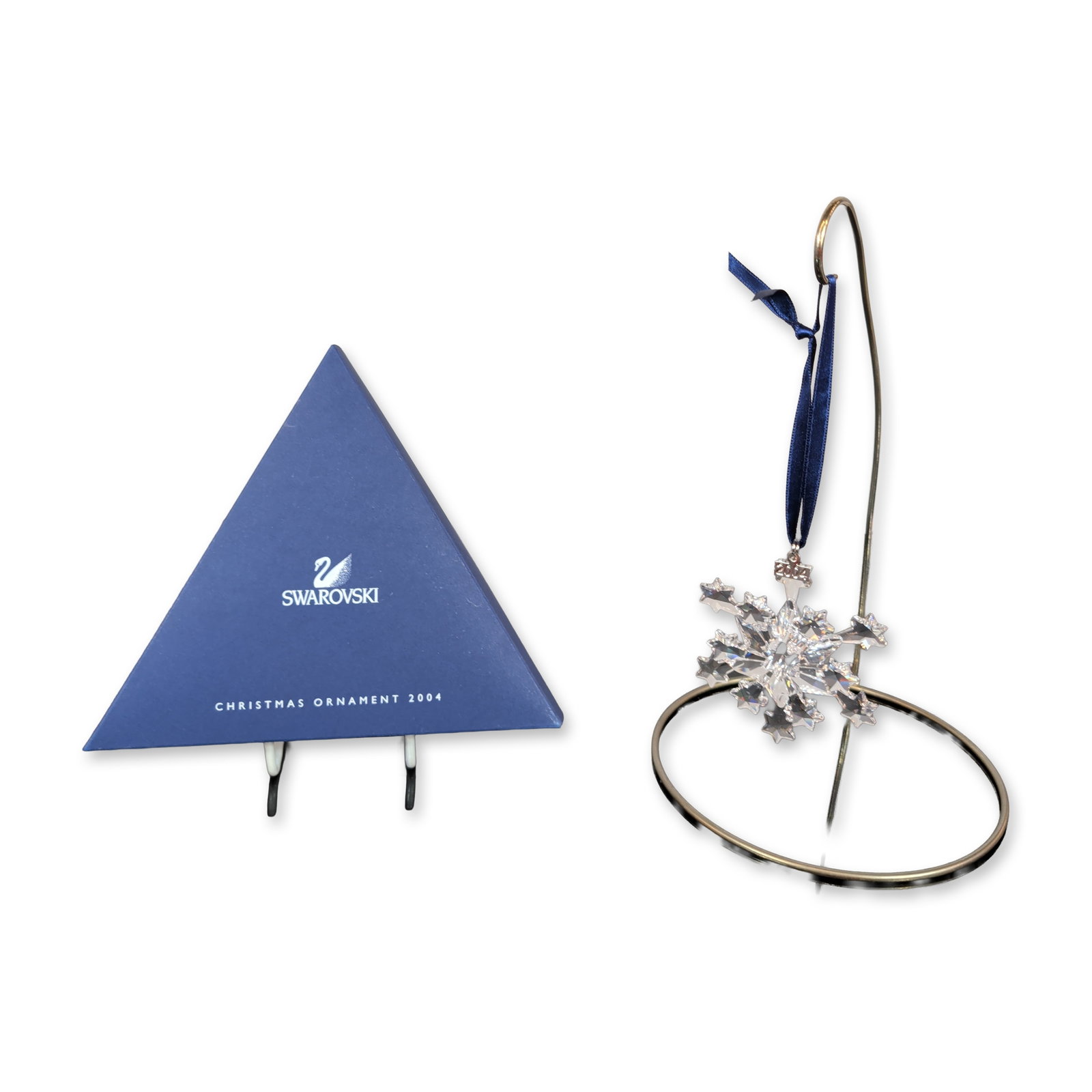 Swarovski 2004 Annual Edition Crystal Snowflake Ornament: Swarovski Annual Edition 2004. Christmas ornament in faceted clear lead crystal, featuring a six-point snowflake design with star-shaped terminal facets. The ornament is suspended from a navy blue sat