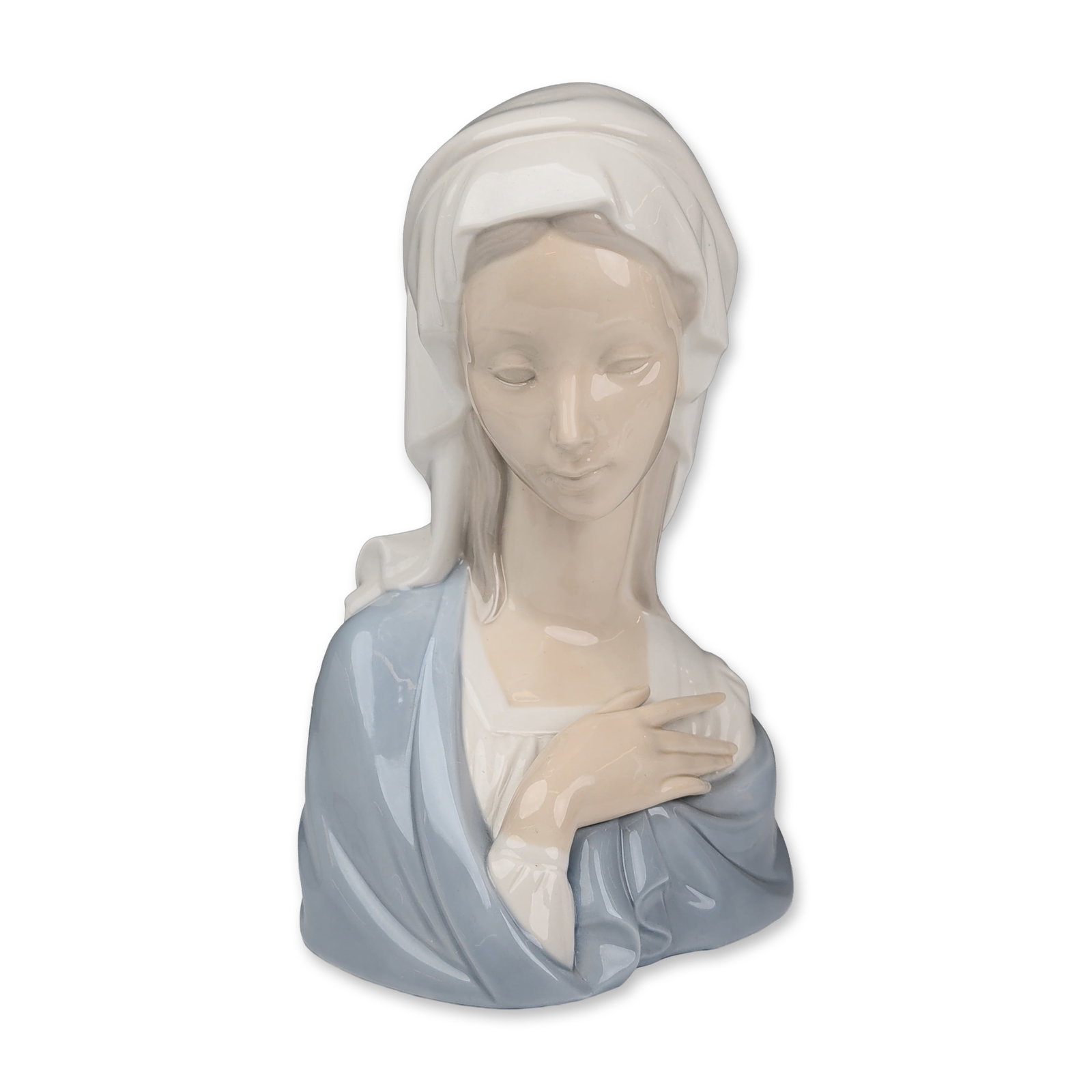 Lladro Glazed Porcelain Madonna Head 01004649: The figure depicts the Virgin Mary in a contemplative pose with her head inclined and right hand placed over her chest. The piece is finished in the classic Lladro palette of soft blue, white, and pal