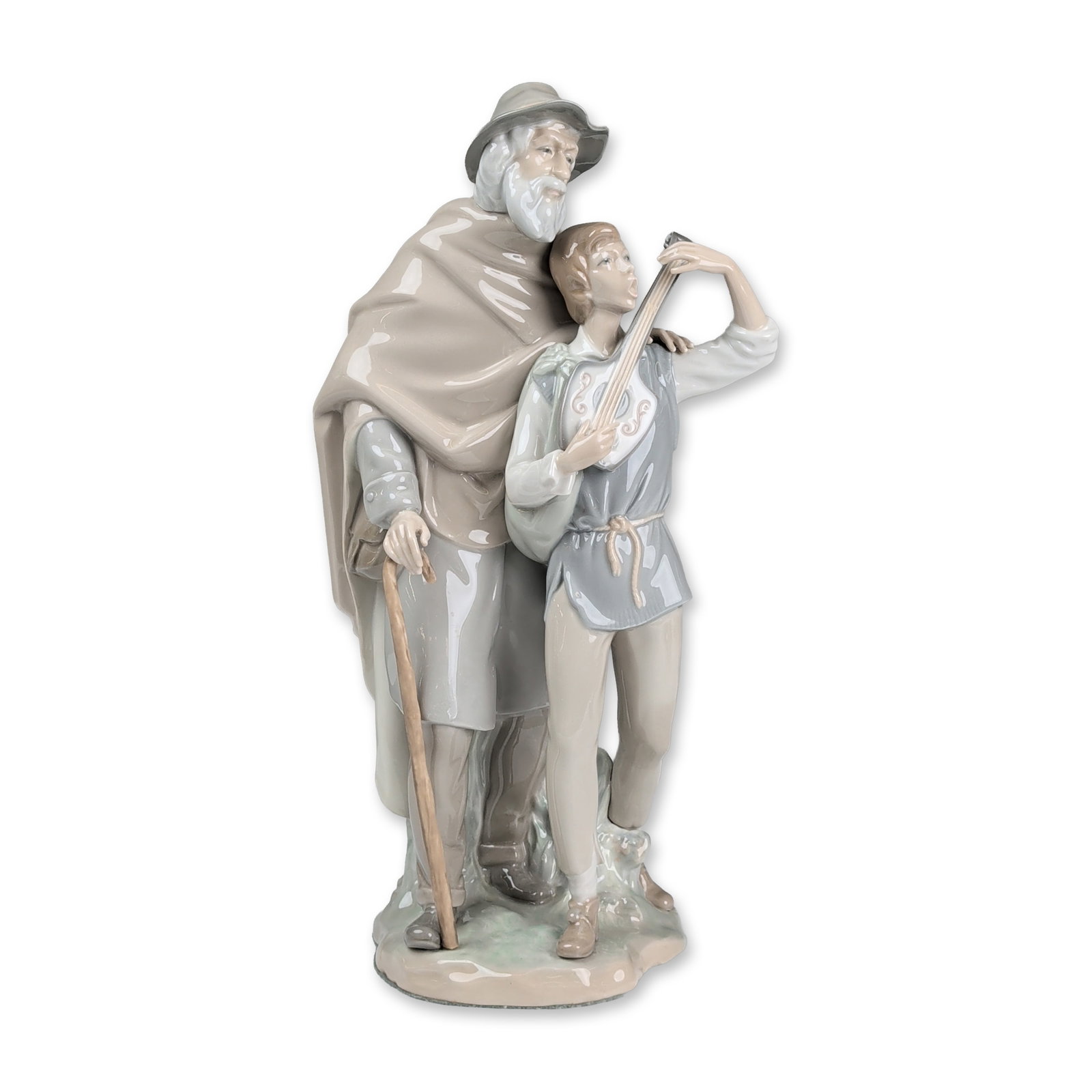 Lladro Porcelain Figurine, Happy Travelers 01004652: Sculpted by Salvador Furio the composition features an elderly man in a tan hooded cloak and grey hat holding a textured staff, standing beside a young boy playing a mandolin. Rendered in a palette of