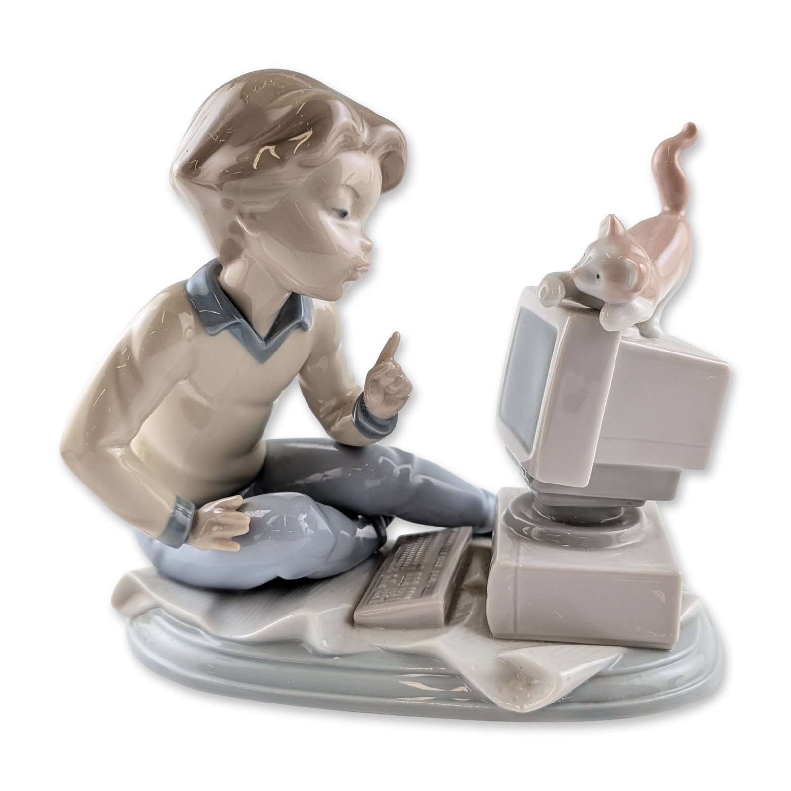 Lladro Programming Pals Porcelain Figurine: Lladro (Spain). Glazed porcelain figurine titled Programming Pals, model number 6693, designed by Juan Aliena. The sculpture depicts a young boy in a beige sweater and blue-gray trousers seated before