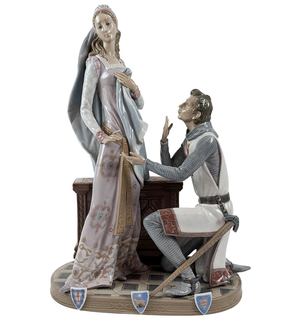 Lladro Spanish Glazed Porcelain Camelot Figurine: Lladro (Spanish, 20th century). Glazed porcelain figural group titled Camelot, model number 1458. The scene depicts a medieval knight in chainmail and a white surcoat with a red cross, kneeling before