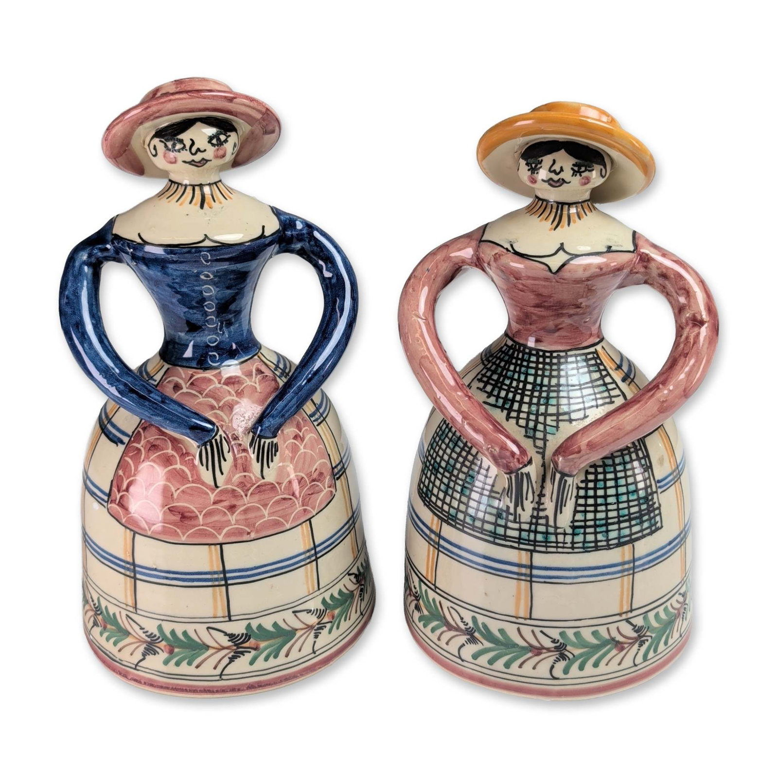 Pair of Spanish Hand Painted Ceramic Figural Bells: Pair of Spanish figural bells in hand-painted glazed ceramic, depicting two women in stylized traditional folk dress. One figure is decorated with a pink bodice and green cross-hatched skirt, while th
