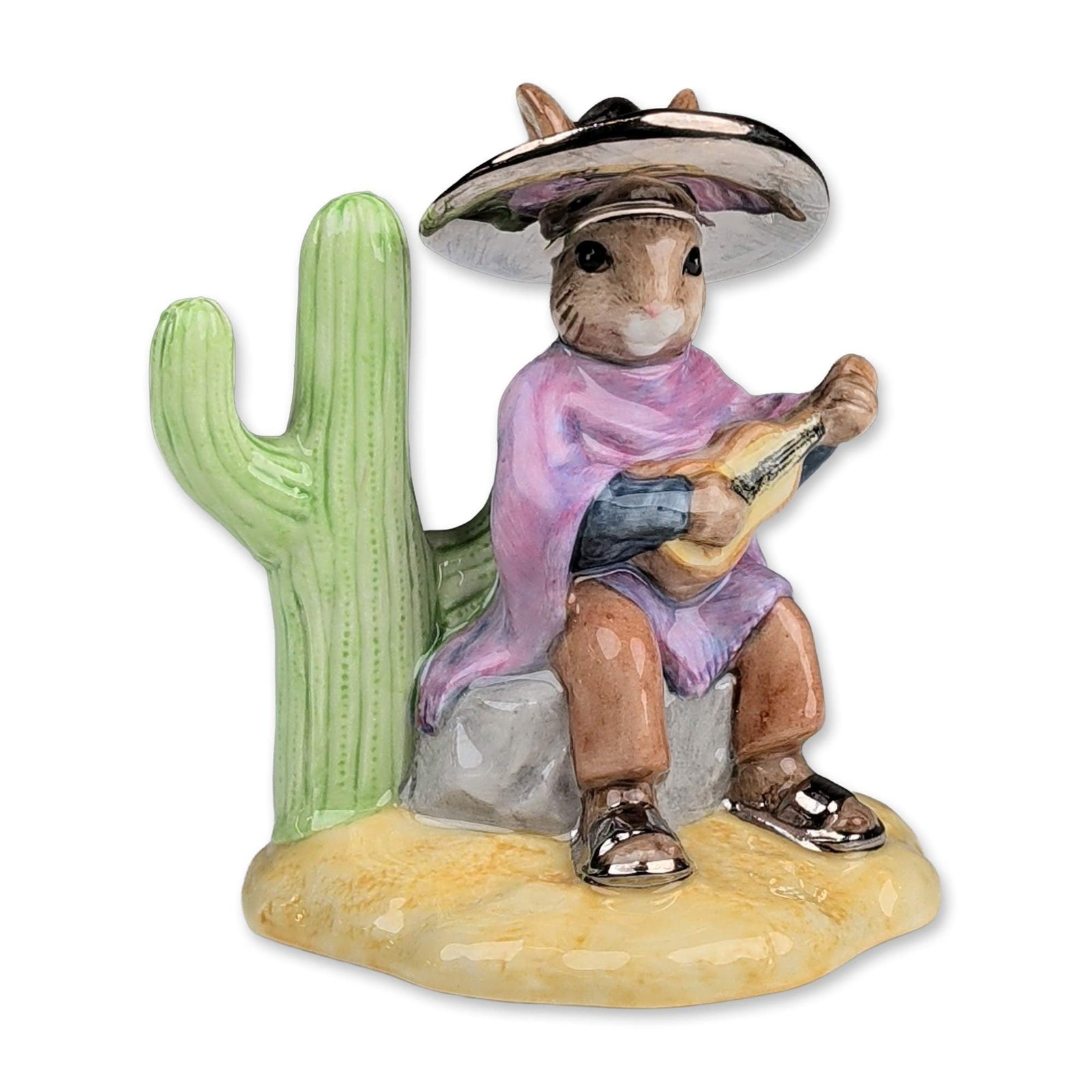 Royal Doulton Silver Mexican Bunnykins Figurine: Royal Doulton. Figurine in hand-decorated fine bone china, depicting a rabbit in a purple tunic and black sombrero playing a guitar while seated beside a saguaro cactus. The sombrero and footwear feat