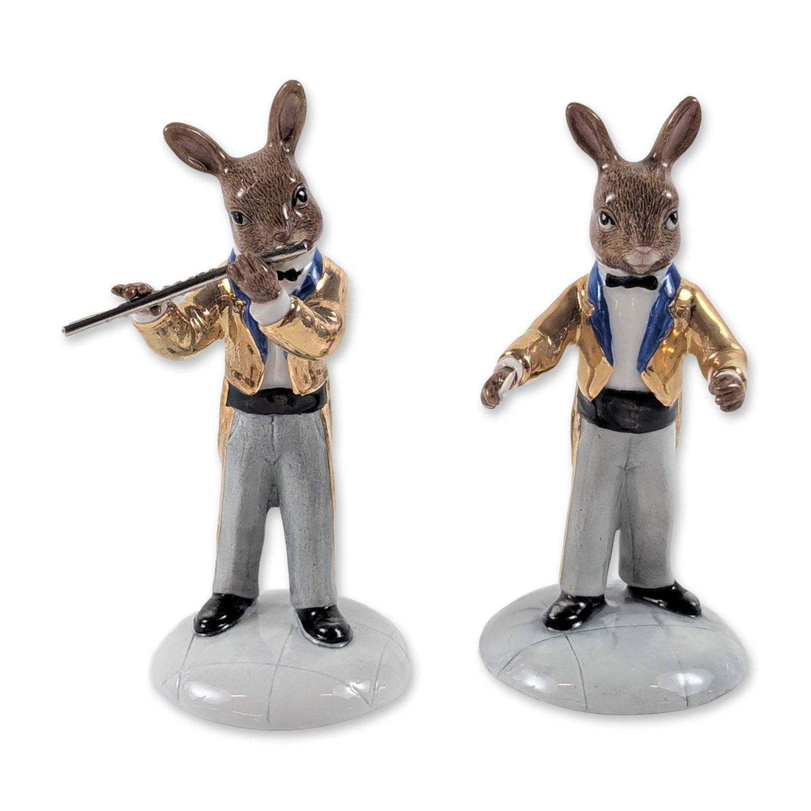 2pc Rare Royal Doulton Bunnykins Orchestra Gold Colorway Figurines: Royal Doulton (England). Pair of porcelain figurines from the Bunnykins Gold Colorway Orchestra series, including The Conductor (DB 396) and The Flute Player (DB 391). Both anthropomorphic rabbits are