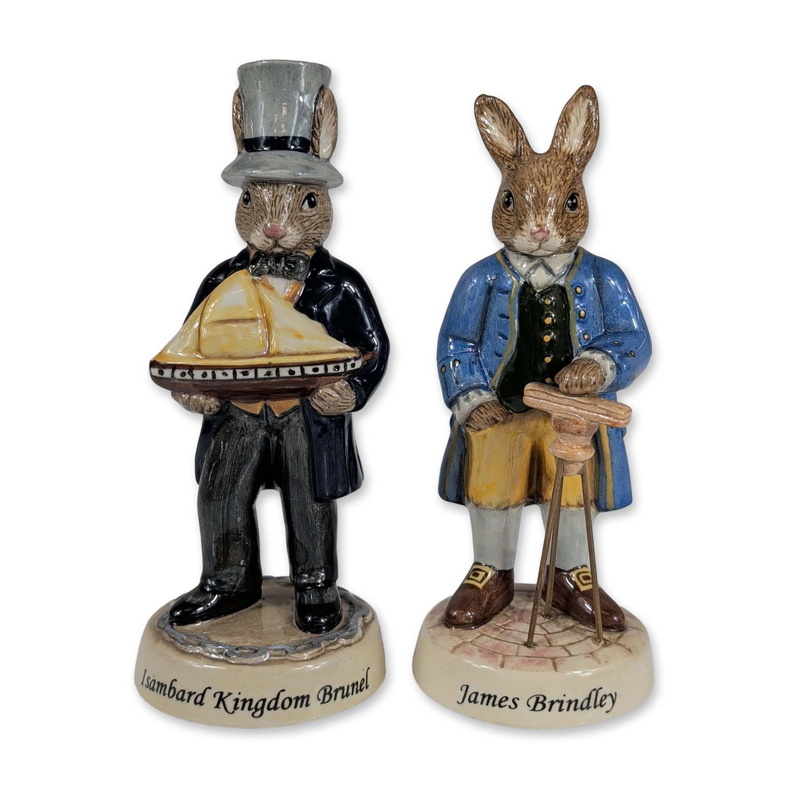 2pc Royal Doulton Bunnykins Inventors Collection Figurines: Royal Doulton, England. Two Bunnykins glazed polychrome ceramic figurines from the Inventors Collection. One figure depicts James Brindley (DB438) in 18th-century attire consisting of a blue coat and 