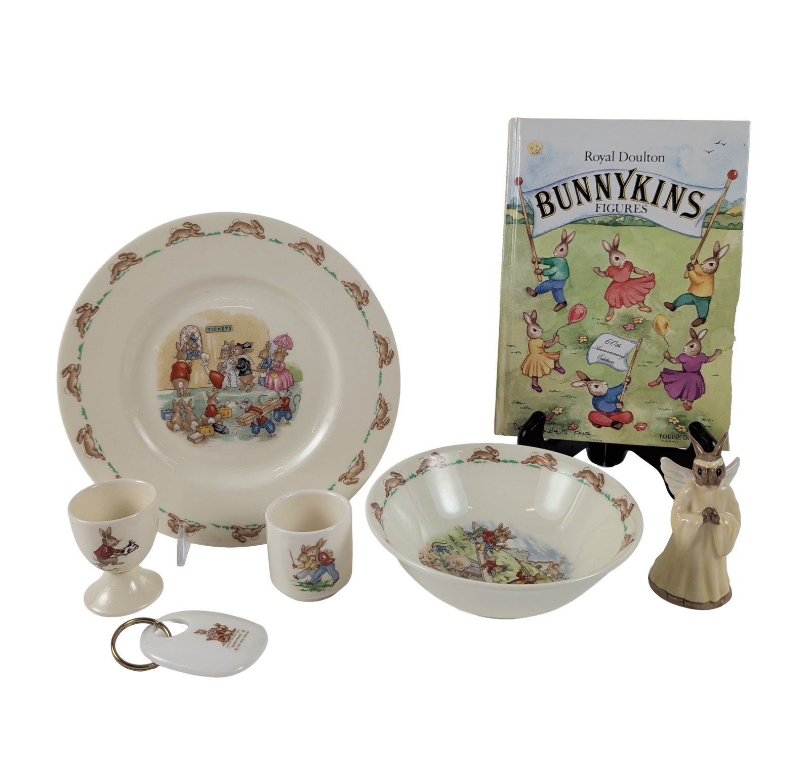 7pc Royal Doulton Bunnykins Ceramic Collection and Signed Book: Collection of Royal Doulton Bunnykins items including fine bone china nursery ware, figurines, and ephemera. The group features a wide-rimmed plate and deep cereal bowl with the characteristic running