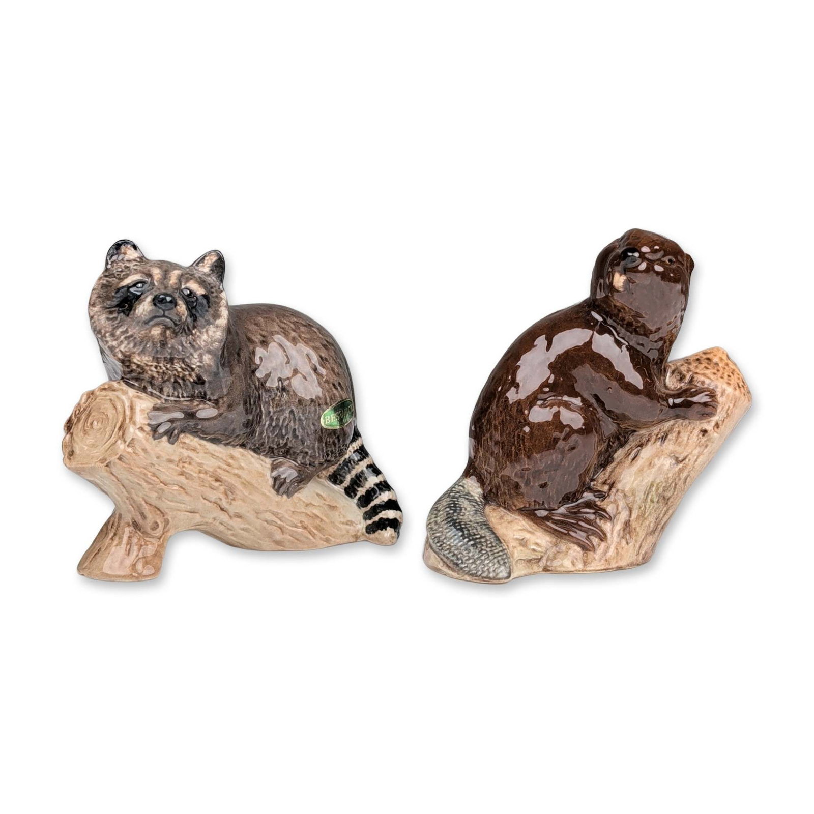 2pc Beswick Ceramic Wildlife Figurines: Beswick, England. Pair of glazed ceramic animal figurines depicting North American wildlife on textured log bases. The set includes a raccoon crouched with a ringed tail and a beaver seated upright in