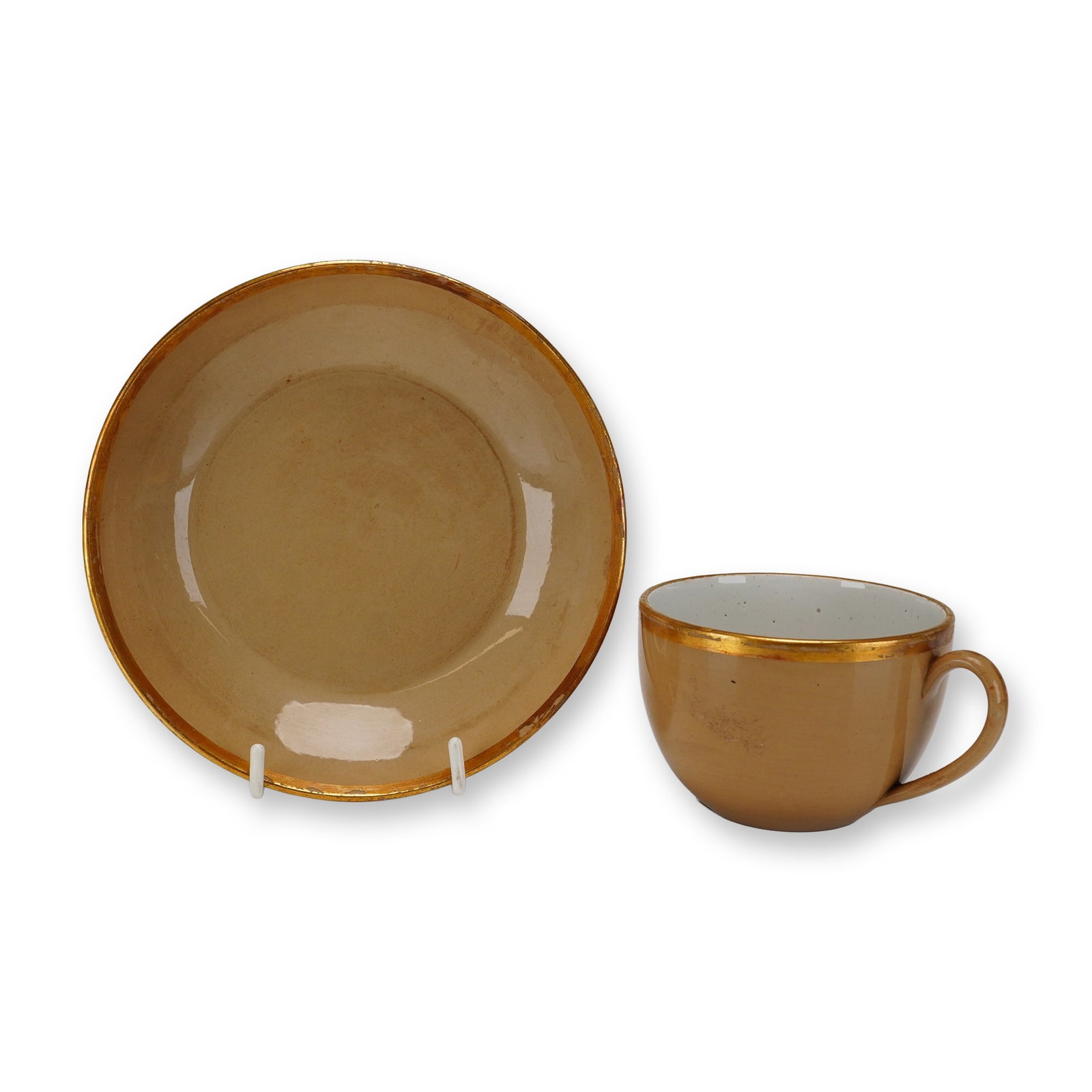 2pc Wedgwood Cane-Colored Glazed Earthenware Teacup and Saucer: This Wedgwood teacup and saucer set features a cane-colored glazed earthenware exterior with a contrasting white-glazed cup interior and simple gilt bands along the rims. The cup has a rounded form wi