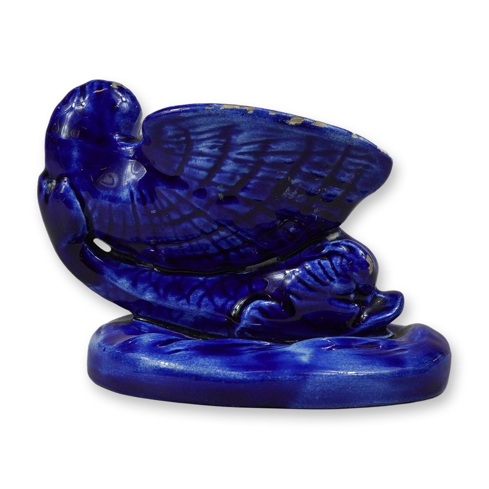 Wedgwood Cobalt Blue Glazed Ceramic Dolphin and Shell Open Salt: This stylized ceramic open salt depicts a dolphin with a shell on its back. The piece is finished in a vibrant, mottled cobalt blue glaze with characteristic streaking and pooling. The figure is set o