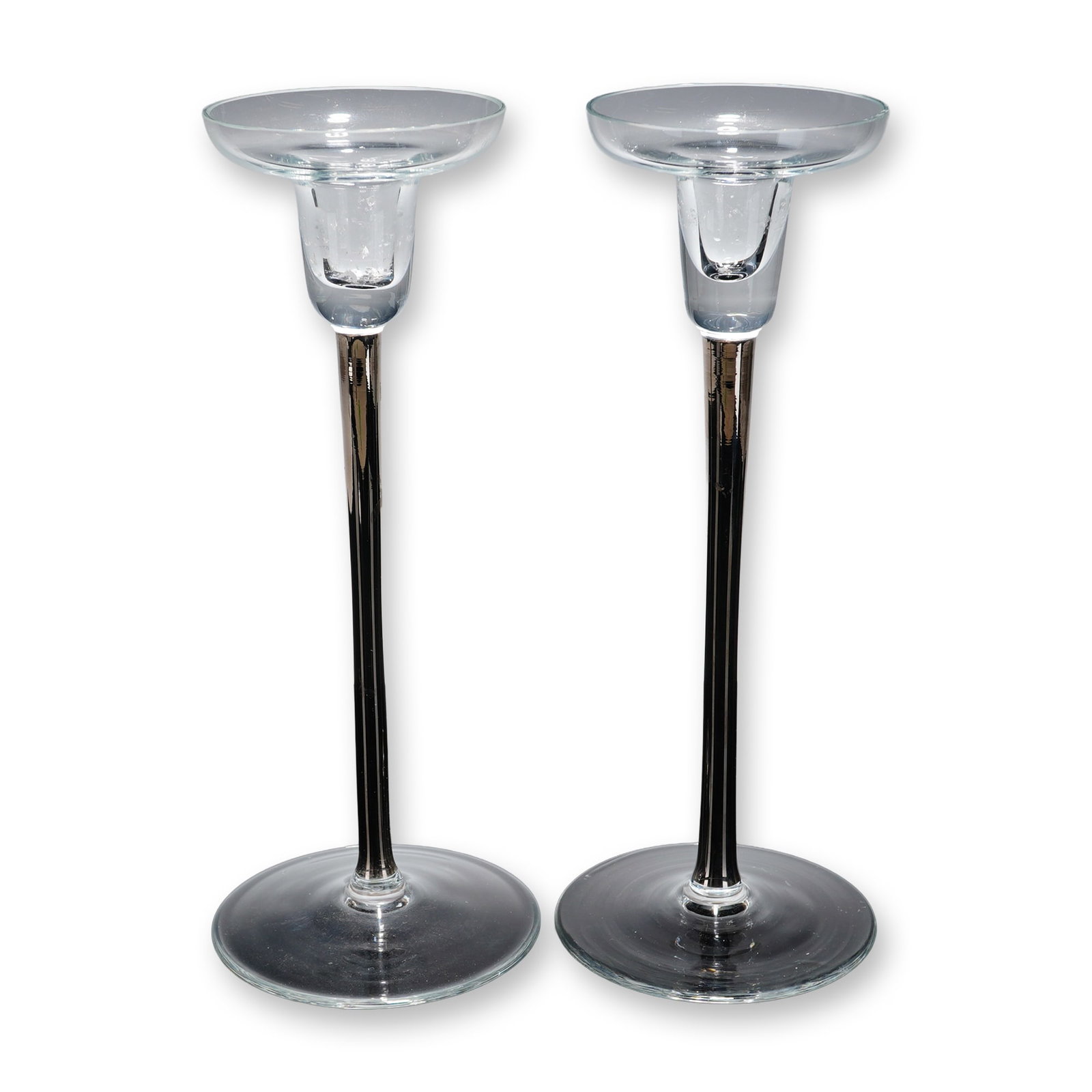 Pair of Clear and Black Stem Minimalist Crystal Candlesticks: A collectible highlighting Pair of Clear and Black Stem Minimalist Crystal Candlesticks. Each piece is constructed with a wide, circular clear glass base and a clear glass candle cup showcasing a flar