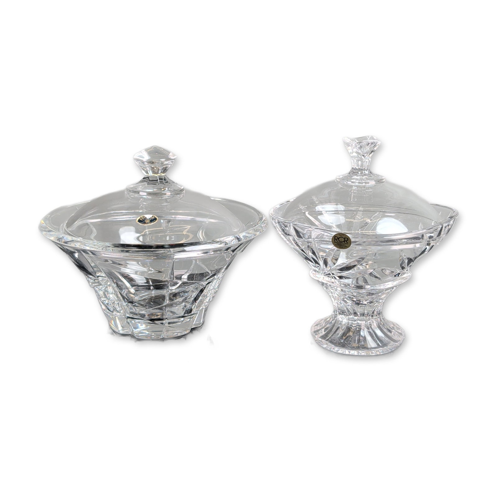 2pc European Cut Lead Crystal Lidded Pedestal Bowls: Two lidded pedestal candy dishes or compotes crafted from heavy lead crystal. The taller vessel is by Royal Crystal Rock (RCR), Italy, featuring deep geometric wedge cuts with starburst and fan motifs