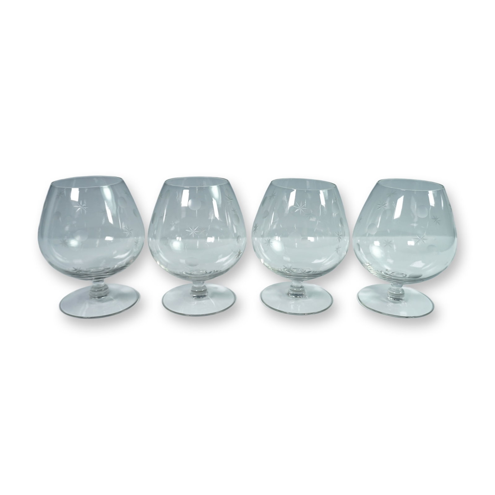 4-Piece Star and Dot Etched Brandy Glasses: A collectible highlighting 4-Piece Star and Dot Etched Brandy Glasses. Set of four clear glass brandy snifters, each showcasing a rounded bowl, short stem, and broad footed base. The glasses are decor