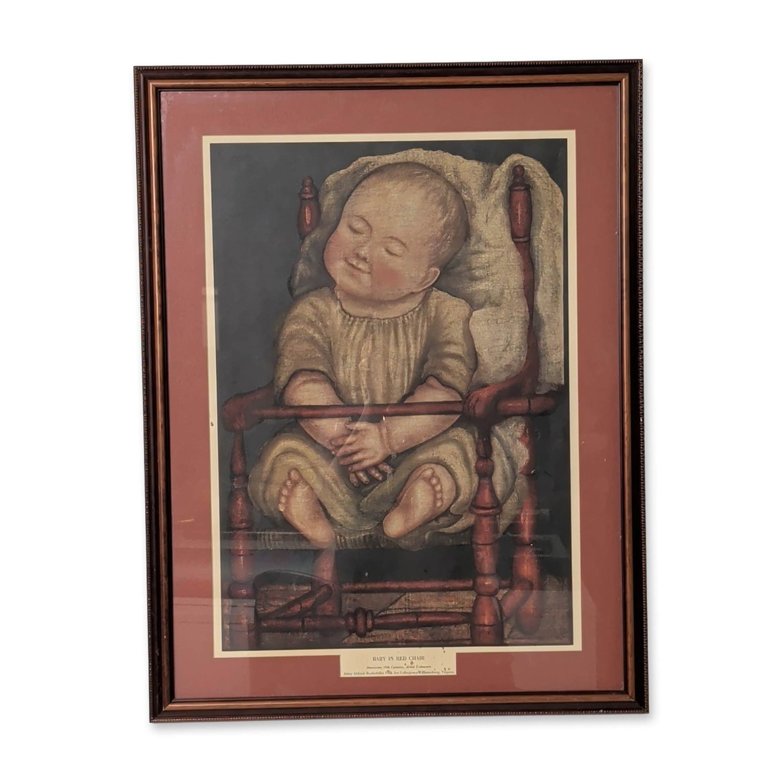Abby Aldrich Rockefeller Folk Art Collection Lithograph on Paper, Baby in Red Chair: Framed lithograph on paper of a 19th-century American folk-art painting titled Baby in Red Chair. The image depicts a sleeping infant in a cream-colored gown nestled within a red-painted wooden spindl