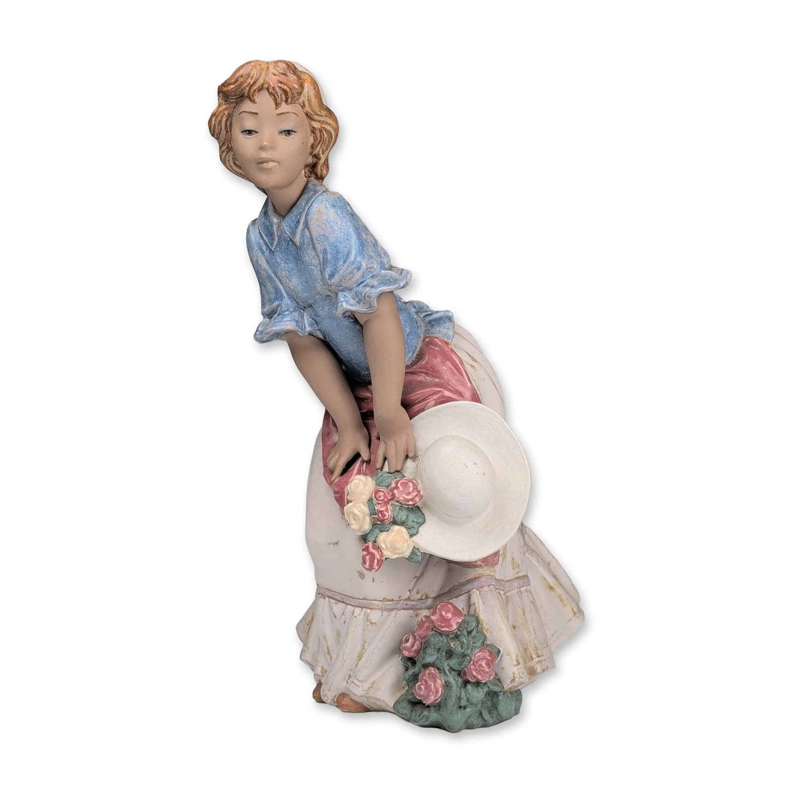 Lladro Gres Porcelain Sculpture, Maiden 01013506: The piece depicts a young girl dressed in a textured blue blouse with ruffled sleeves and a cream-colored tiered skirt with pink accents designed by Salvador Debon. She holds a wide-brimmed hat filled