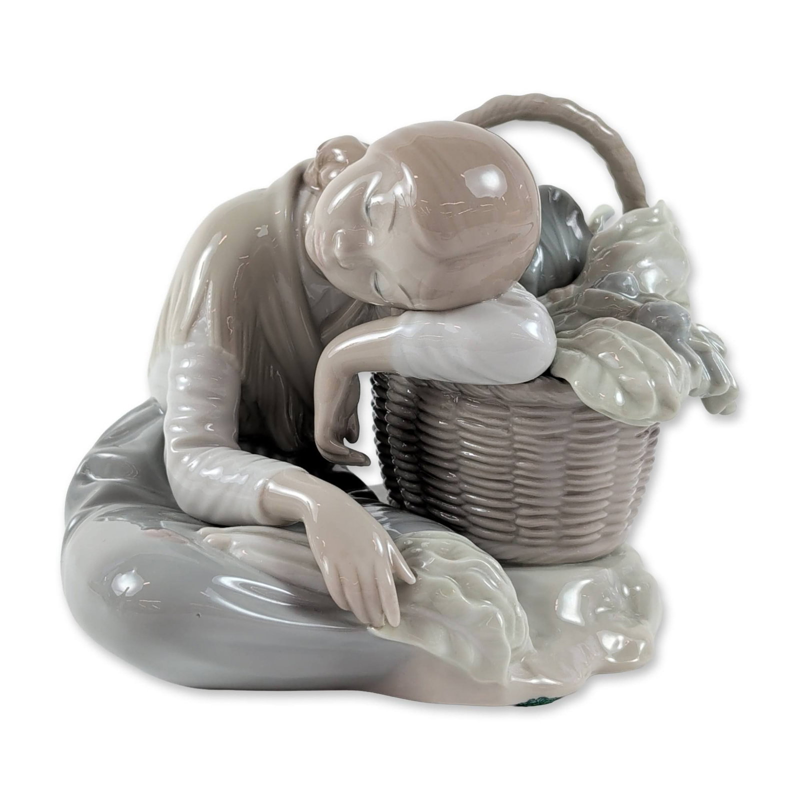 Lladro Spanish Glazed Porcelain Cabbage Seller Figurine: Lladro (Spanish, late 20th century) glazed porcelain figurine titled Cabbage Seller, model number 1087, designed by Antonio Ballester. It shows a kneeling youth in rustic attire next to a large, textu