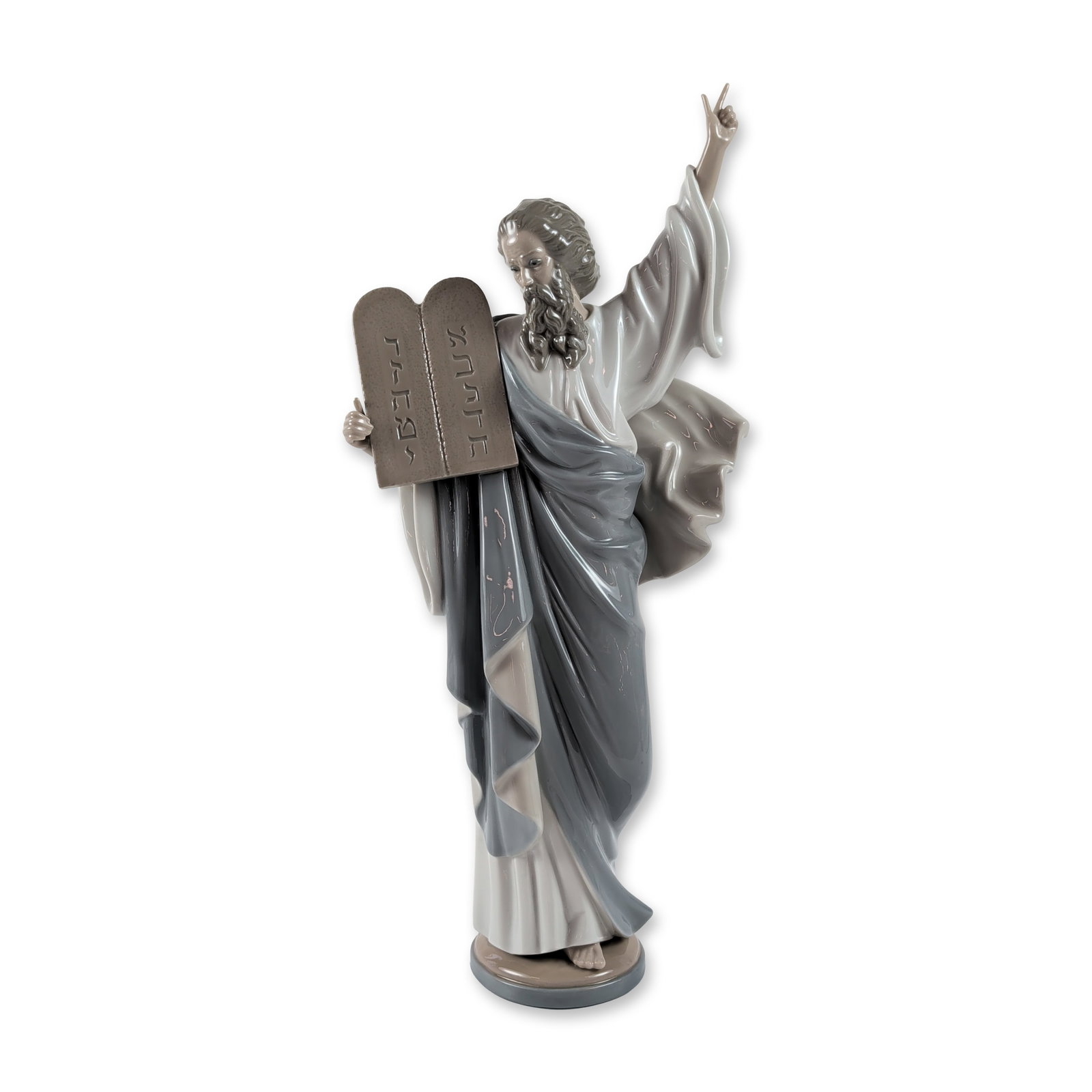 Lladro Porcelain Sculpture, Moses 1005170: Designed by sculptor Francisco Catala. The figure is depicted in a dramatic pose with the right arm raised and index finger pointing upward, while the left arm holds the tablets of the Ten Commandment