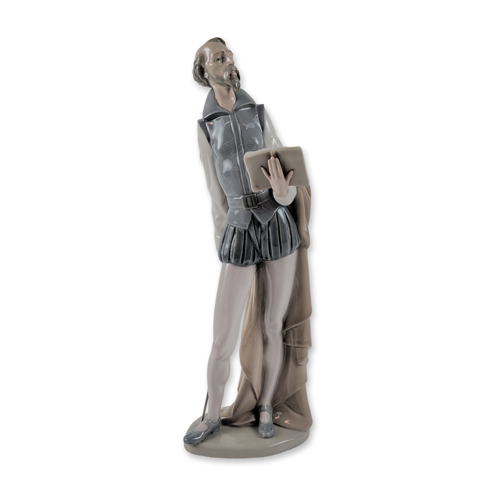 Nao by Lladro Don Quixote Reading Porcelain Figurine: Depicts Don Quixote in 16th-century Spanish attire, including a doublet, trunk hose, and long cloak draped over one arm. He holds a book in his left hand while his right hand rests on the hilt of a ra