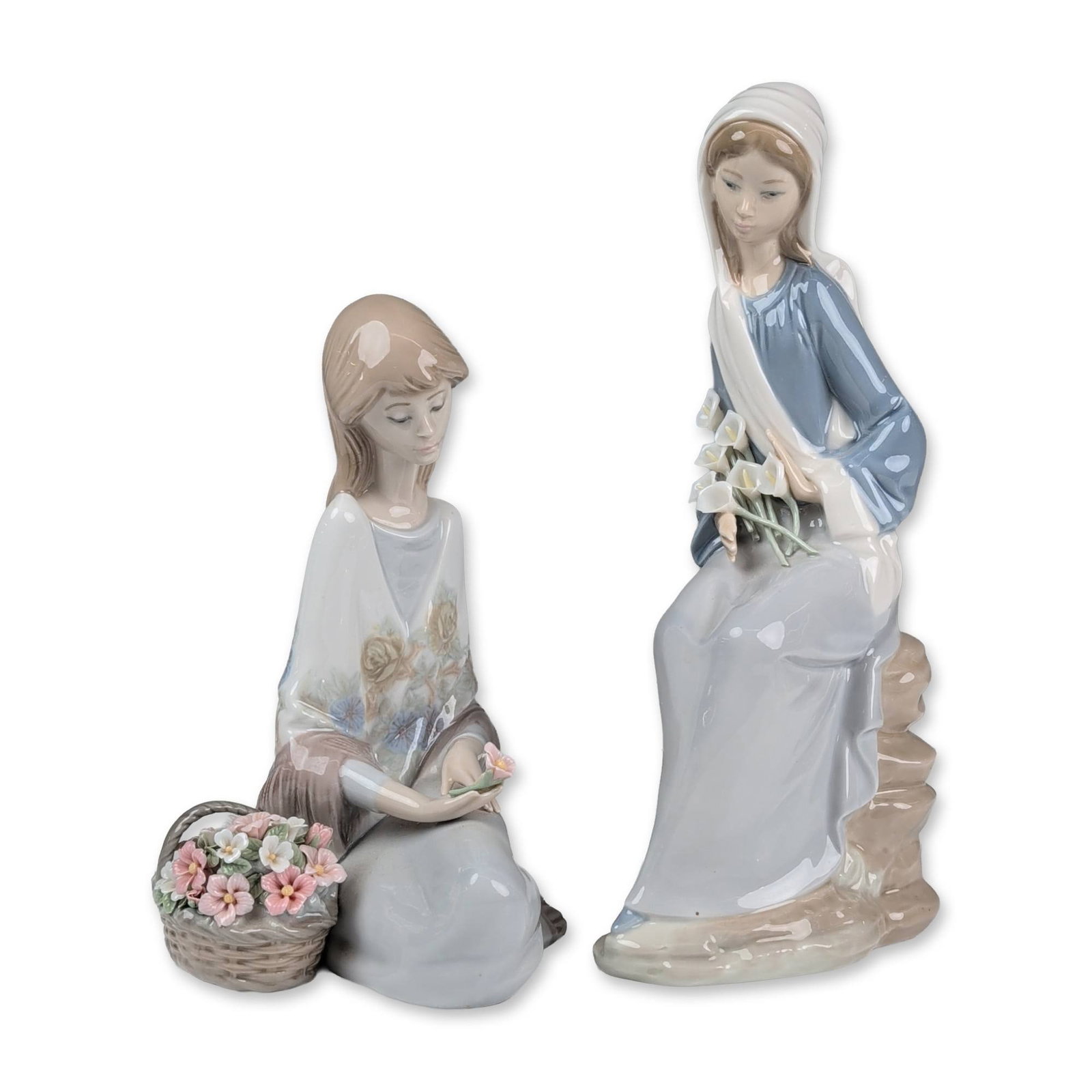 2pc Lladro Porcelain Figurines, Flower Song and Girl with Lilies Sitting: Two glazed porcelain figurines featuring young female subjects with flowers. The first figure, titled Flower Song (1007607), depicts a girl seated beside a basket of colorful blossoms. The second figu