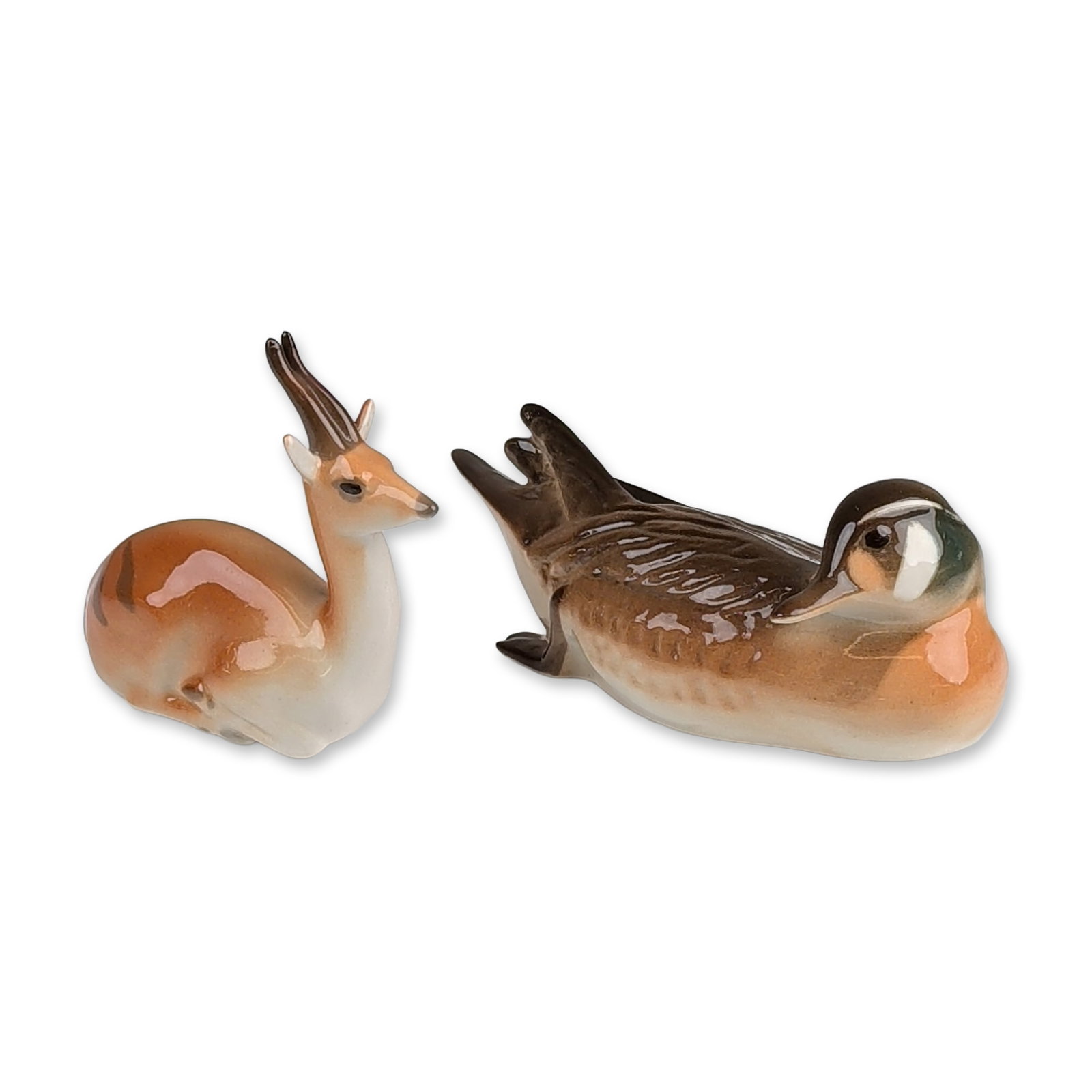 2pc Russian Porcelain Animal Figurines: Lomonosov Porcelain Factory. Two animal figurines in hand-painted glazed porcelain. The first depicts a preening Baikal teal duck with brown and white plumage and green accents to the head. The second