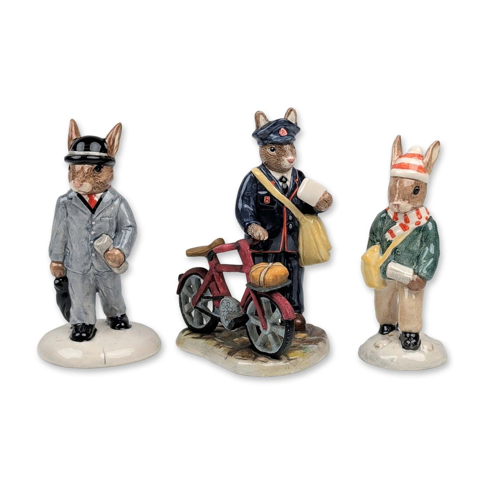 Trio of Royal Doulton Bunnykins Figurines: Trio of Royal Doulton Bunnykins hand-painted porcelain figurines featuring various occupational themes. The group includes Paperboy Bunnykins (DB 77) dressed in a green jacket and red striped scarf wi