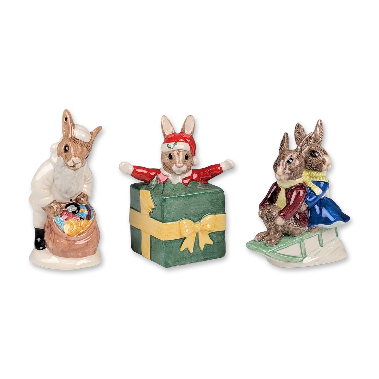 3pc Royal Doulton Bunnykins Figurines: Royal Doulton. Trio of Christmas-themed Bunnykins figurines in glazed polychrome ceramic, including Billie & Buntie on a sleigh, Santa Bunnykins, and Santa's Helper. The Santa's Helper figurine (DB 19