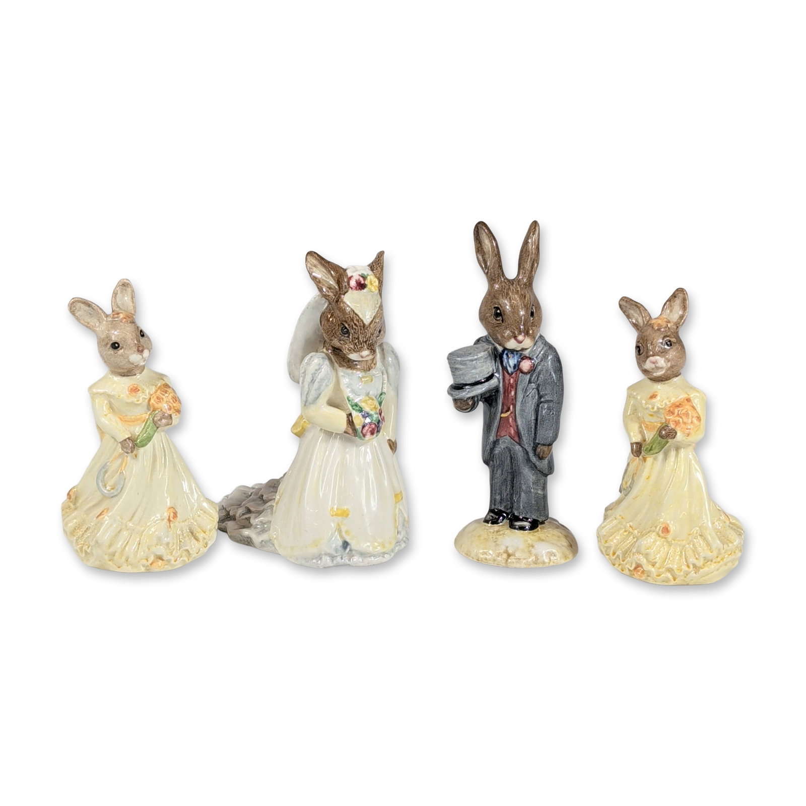 4pc Royal Doulton Bunnykins Wedding Figurines: Royal Doulton glazed porcelain figurines from the Bunnykins collection, depicting a wedding party. The grouping includes a Bride Bunnykins (DB 101) in a white ruffled gown with a veil and floral bouqu